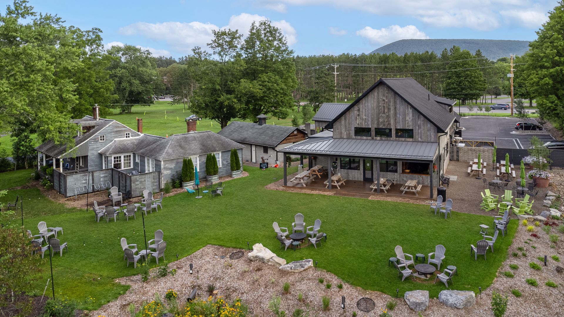 Lush green lawn with outdoor seating in front of weathered gray buildings.