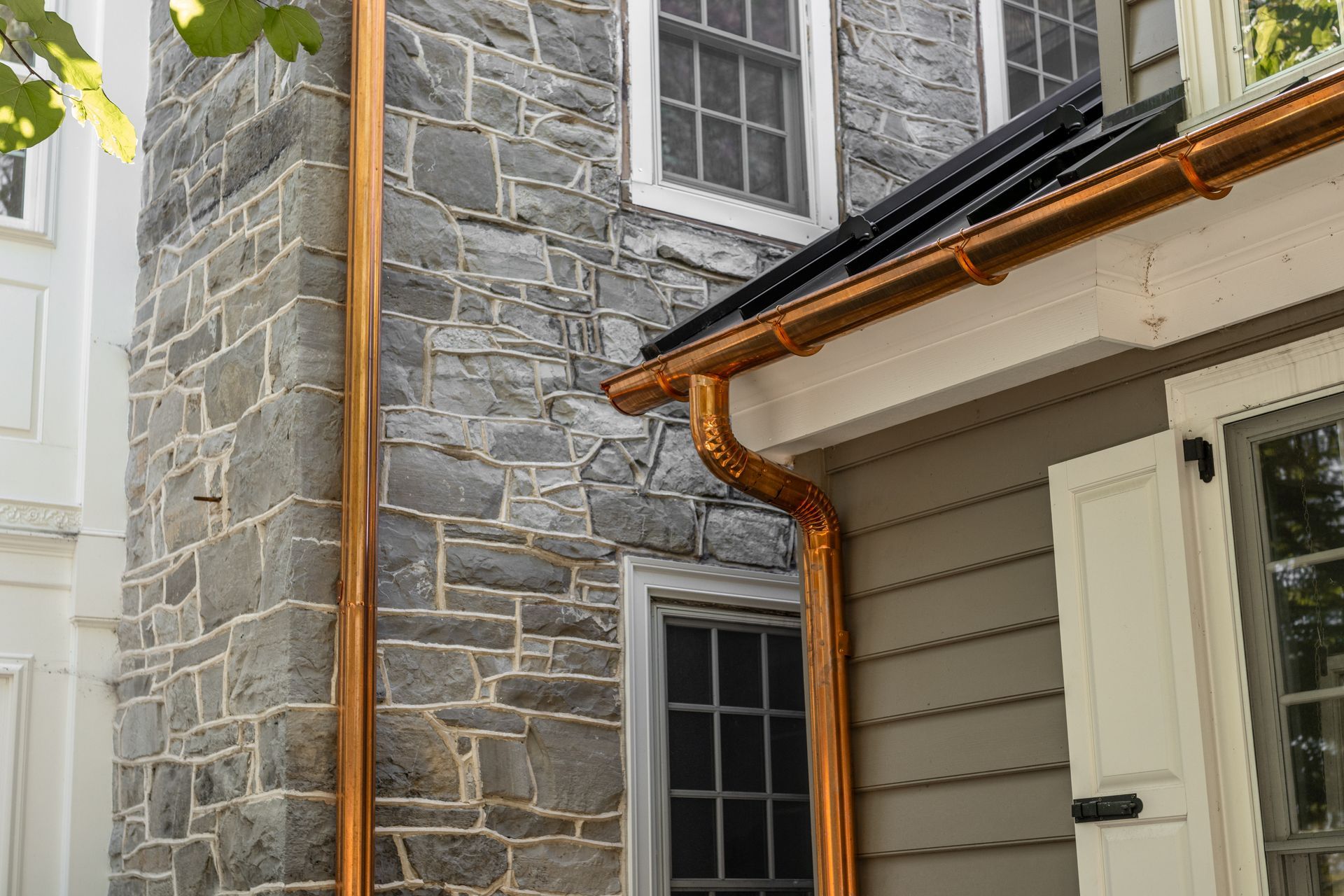 Copper gutters on a stone and siding house.