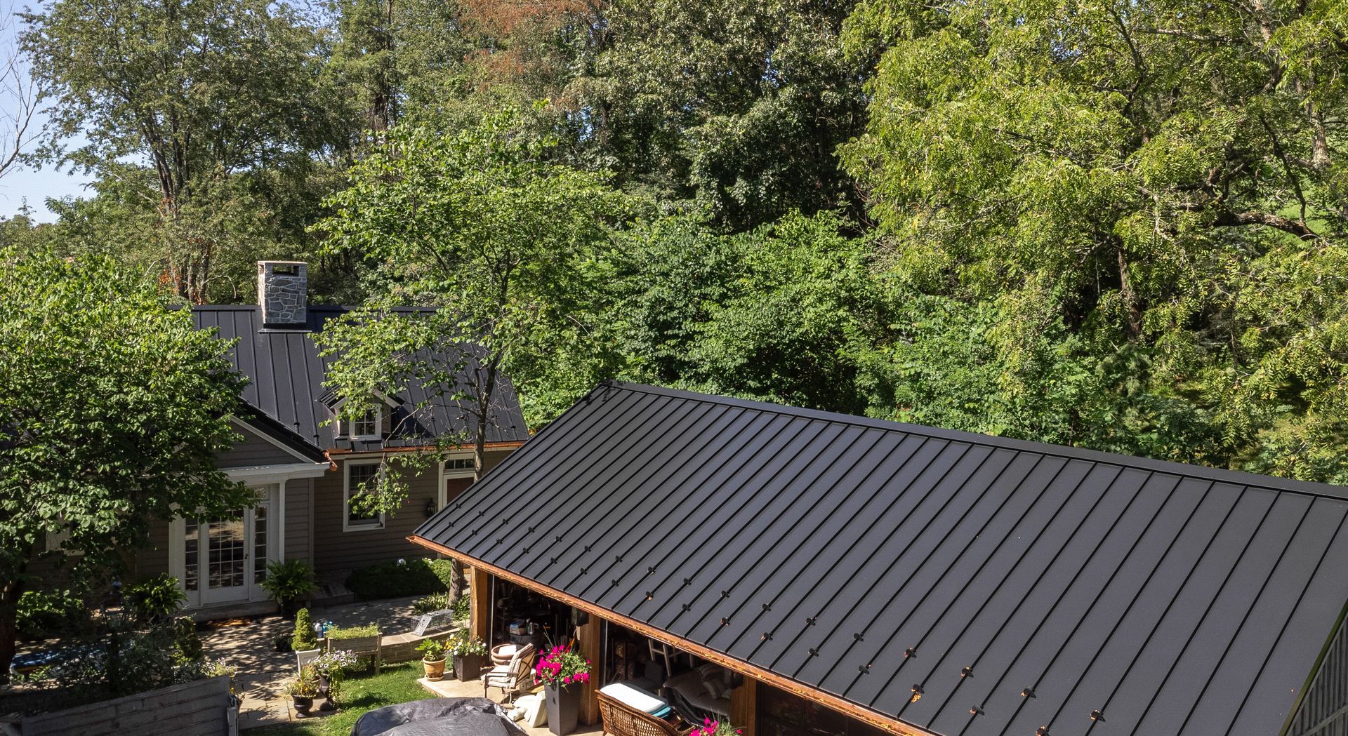 Houses with black roofs surrounded by green trees.