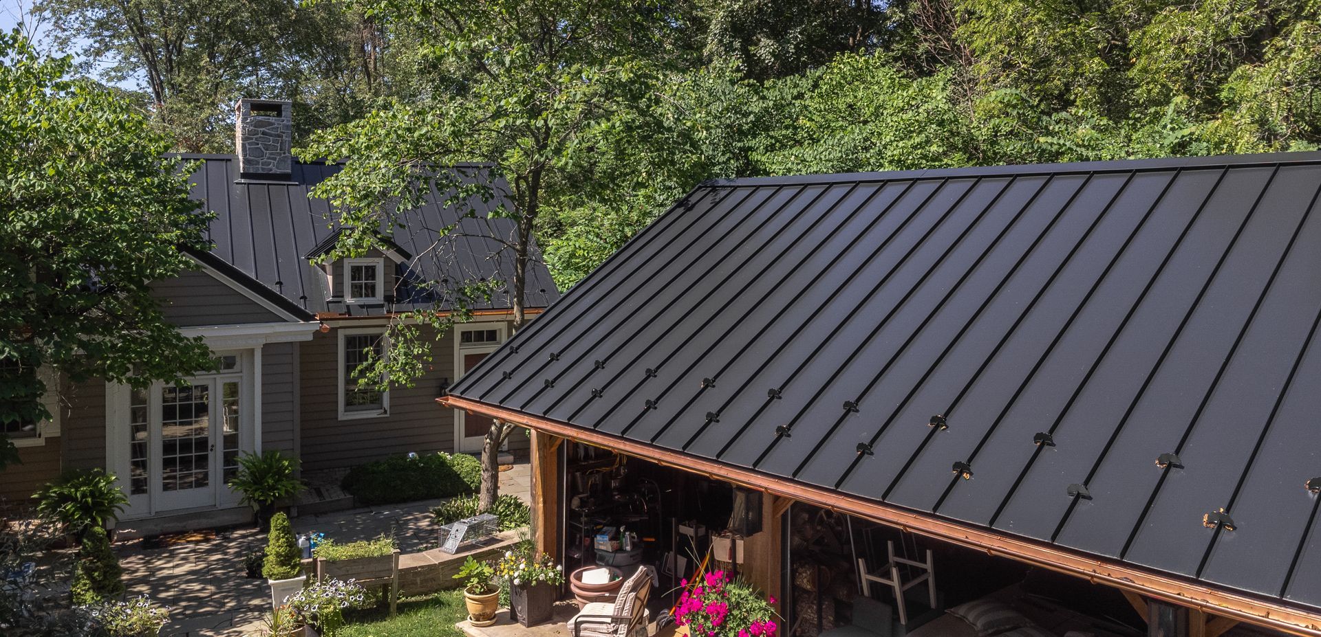 Black metal roofs on houses and a garden area with lush greenery.