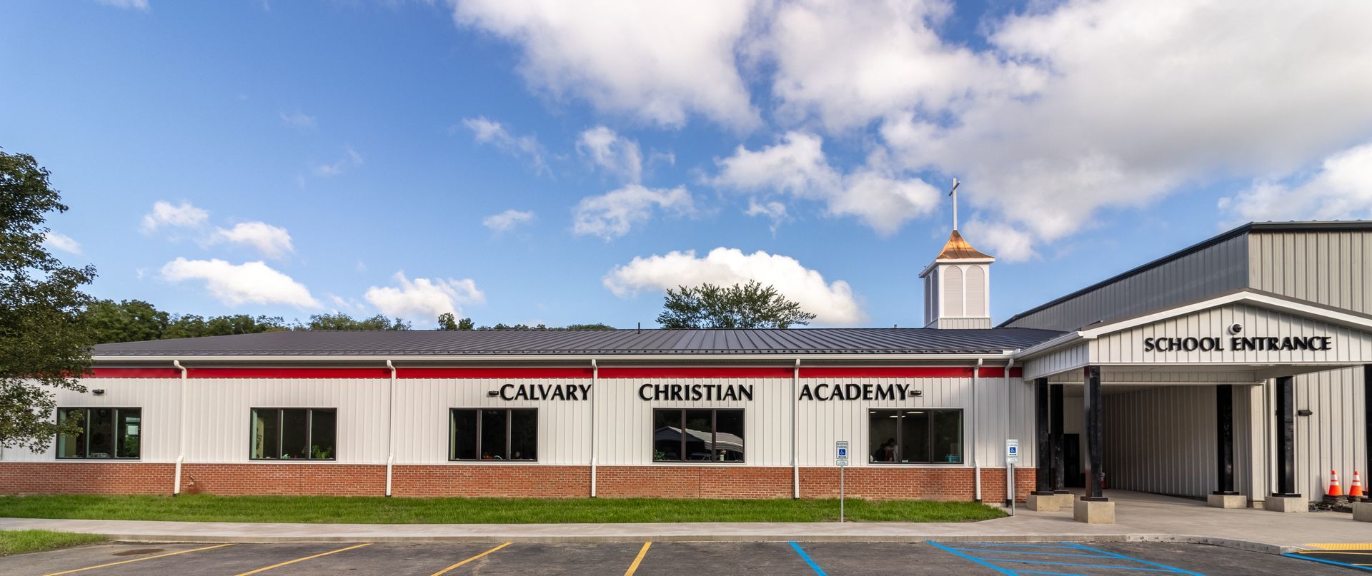 Exterior of Calvary Christian Academy building under a blue sky with clouds.