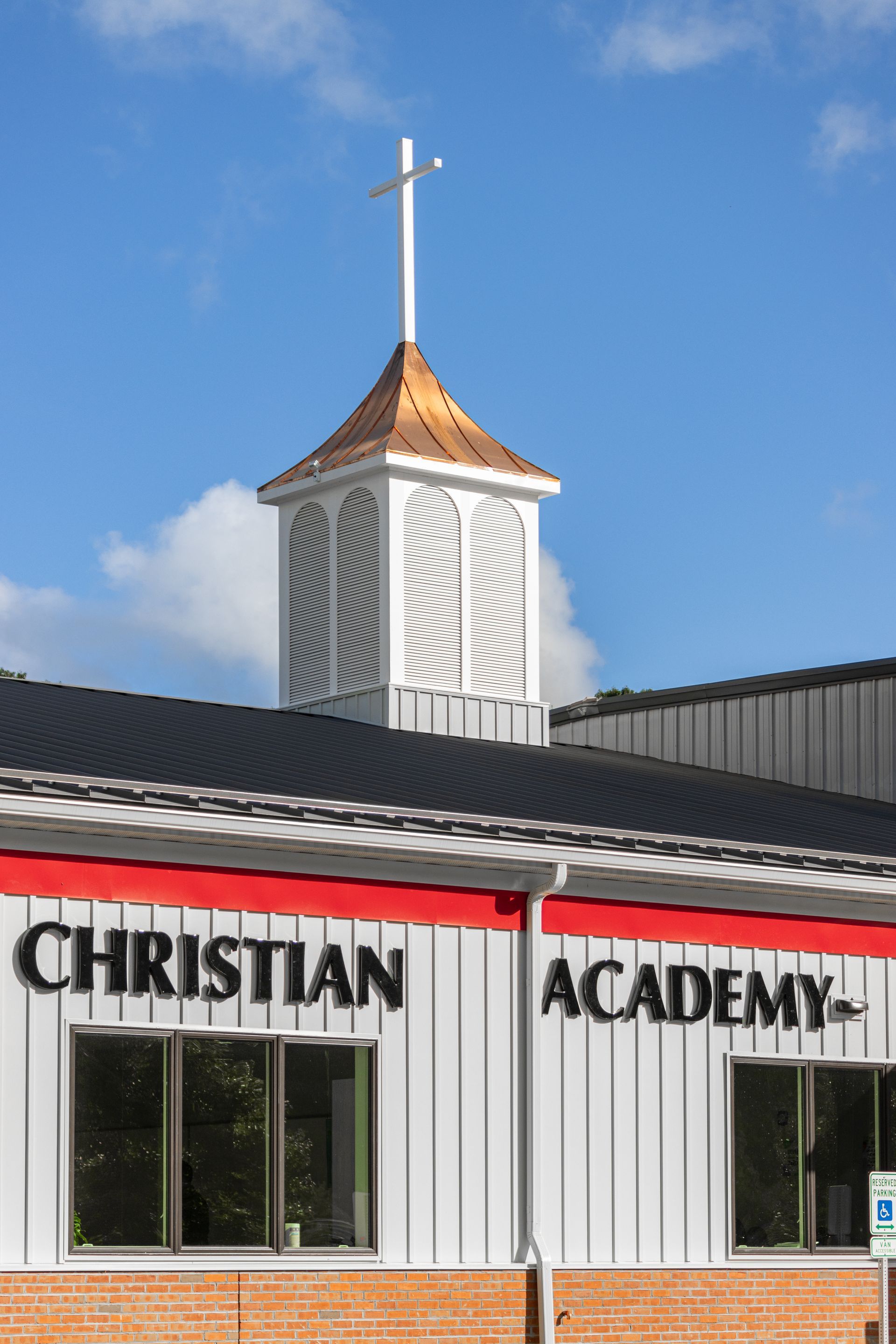 Exterior of Christian Academy building with steeple and cross.