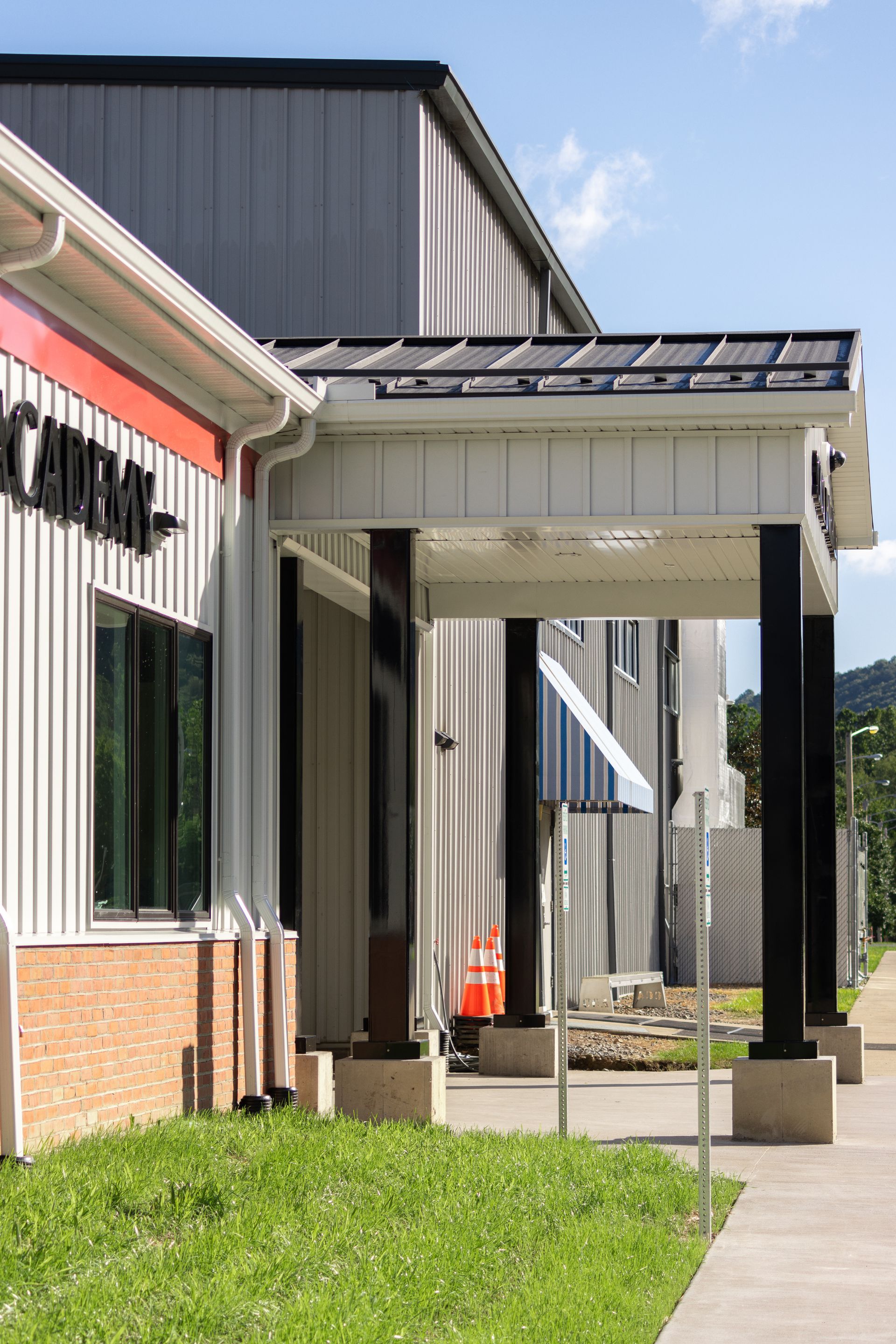 Building with black columns, a red-accented roof, and a sign that says 