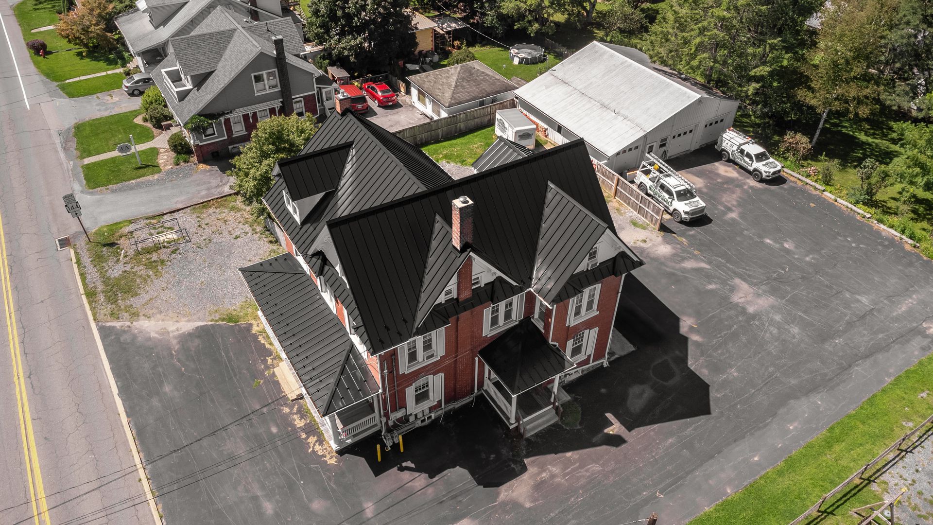 An aerial view of a red brick building with a black roof in a parking lot.