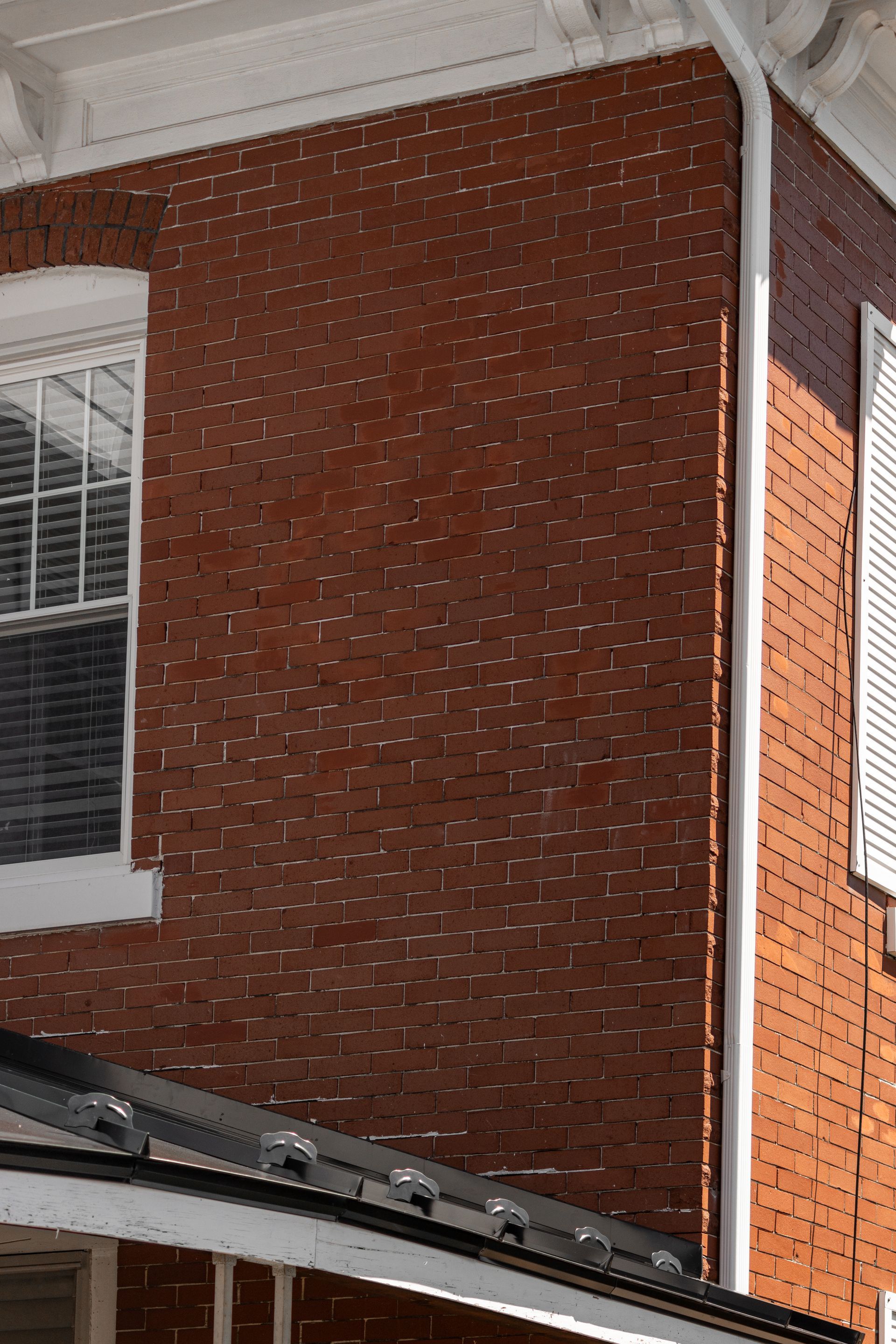 Red brick building exterior with white window, gutter and trim.