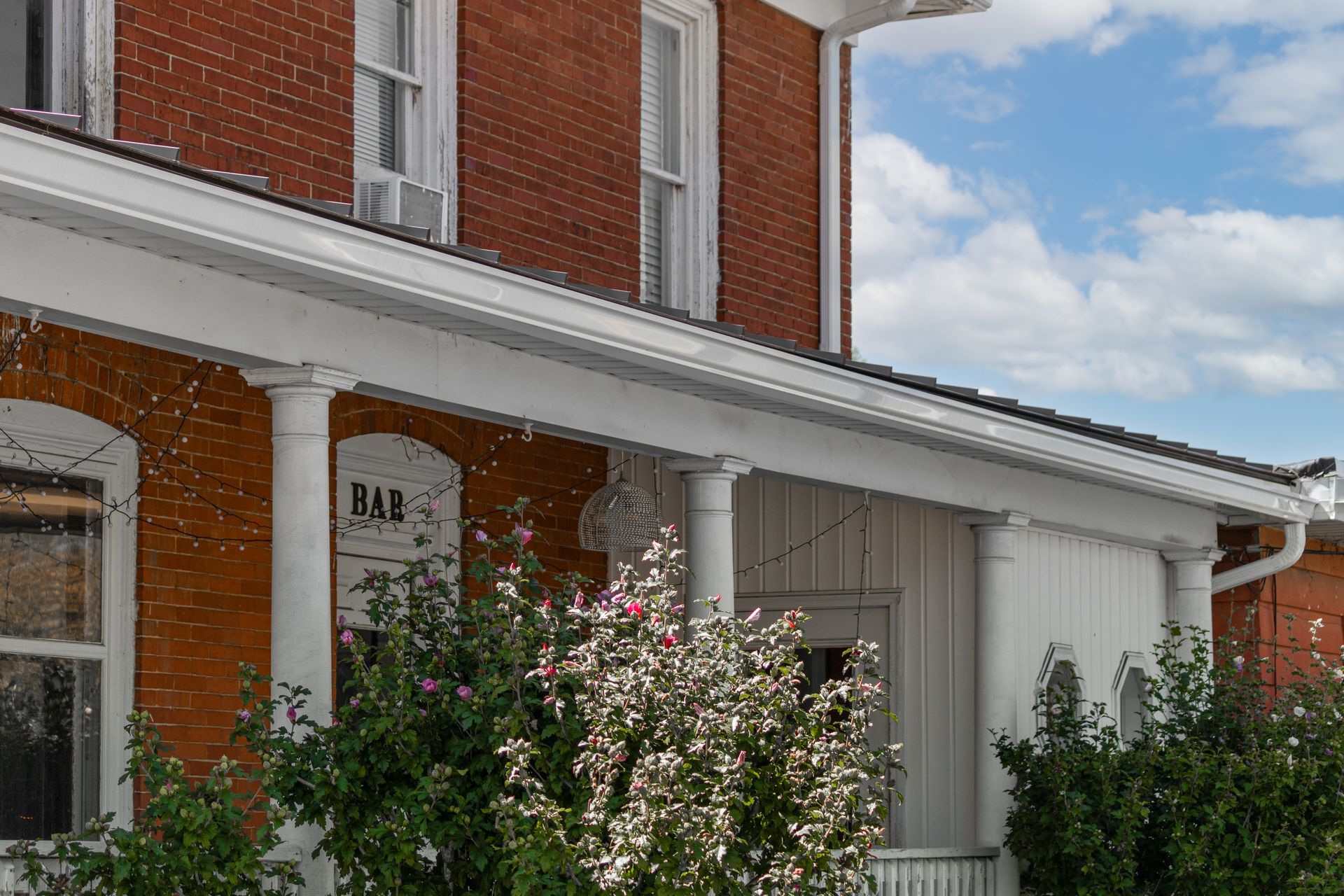Red brick building with white porch, pillars, and trim; blue sky.