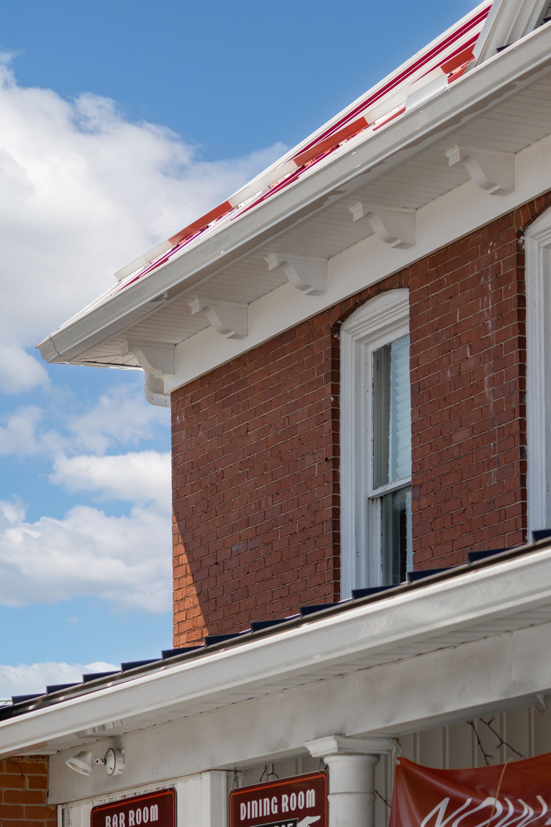 Brick building with white trim, red roof, and blue sky.