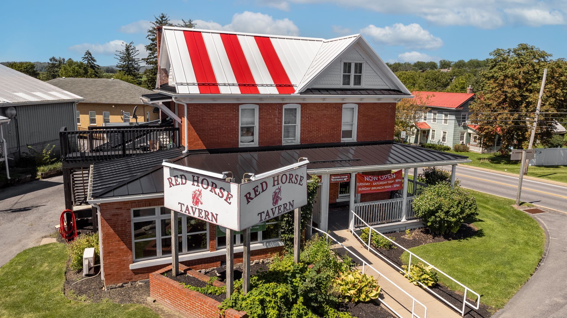 Red Horse Tavern building with red and white striped roof, white sign, and accessible ramp.