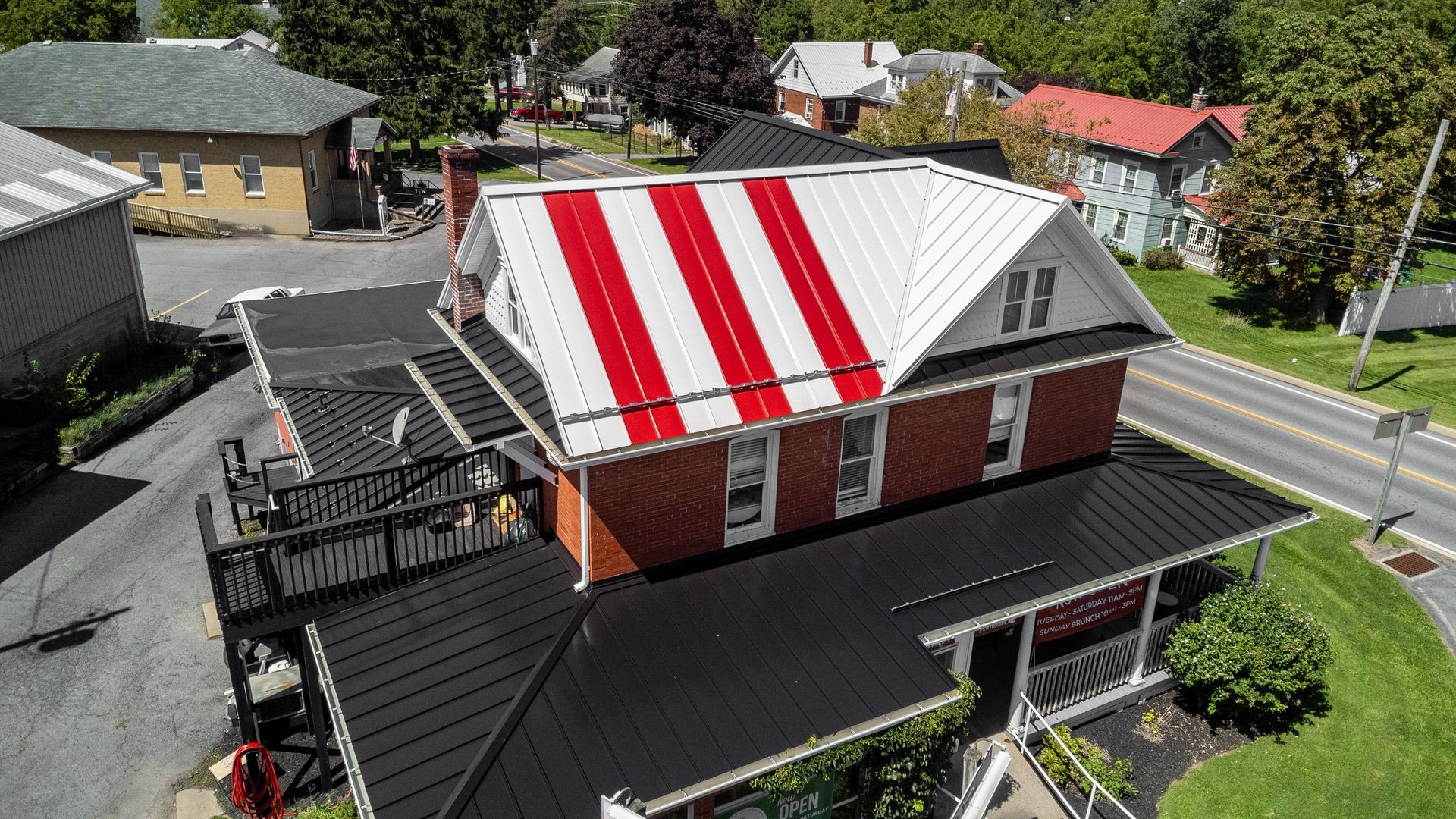 Brick building with a red and white striped roof, black lower roof, and a small deck.