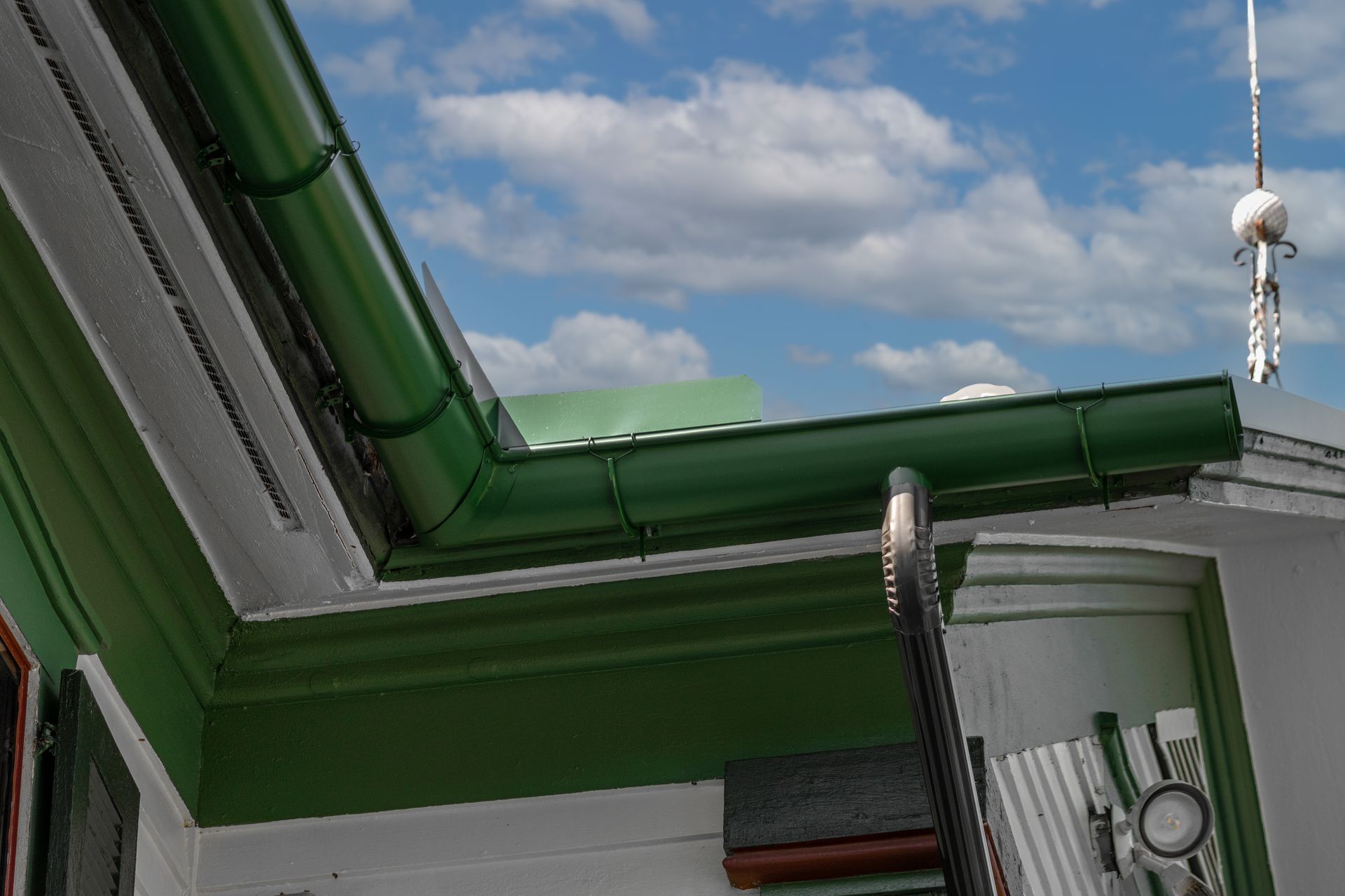 Green gutters and trim on a building, blue sky with clouds in the background, antenna visible.