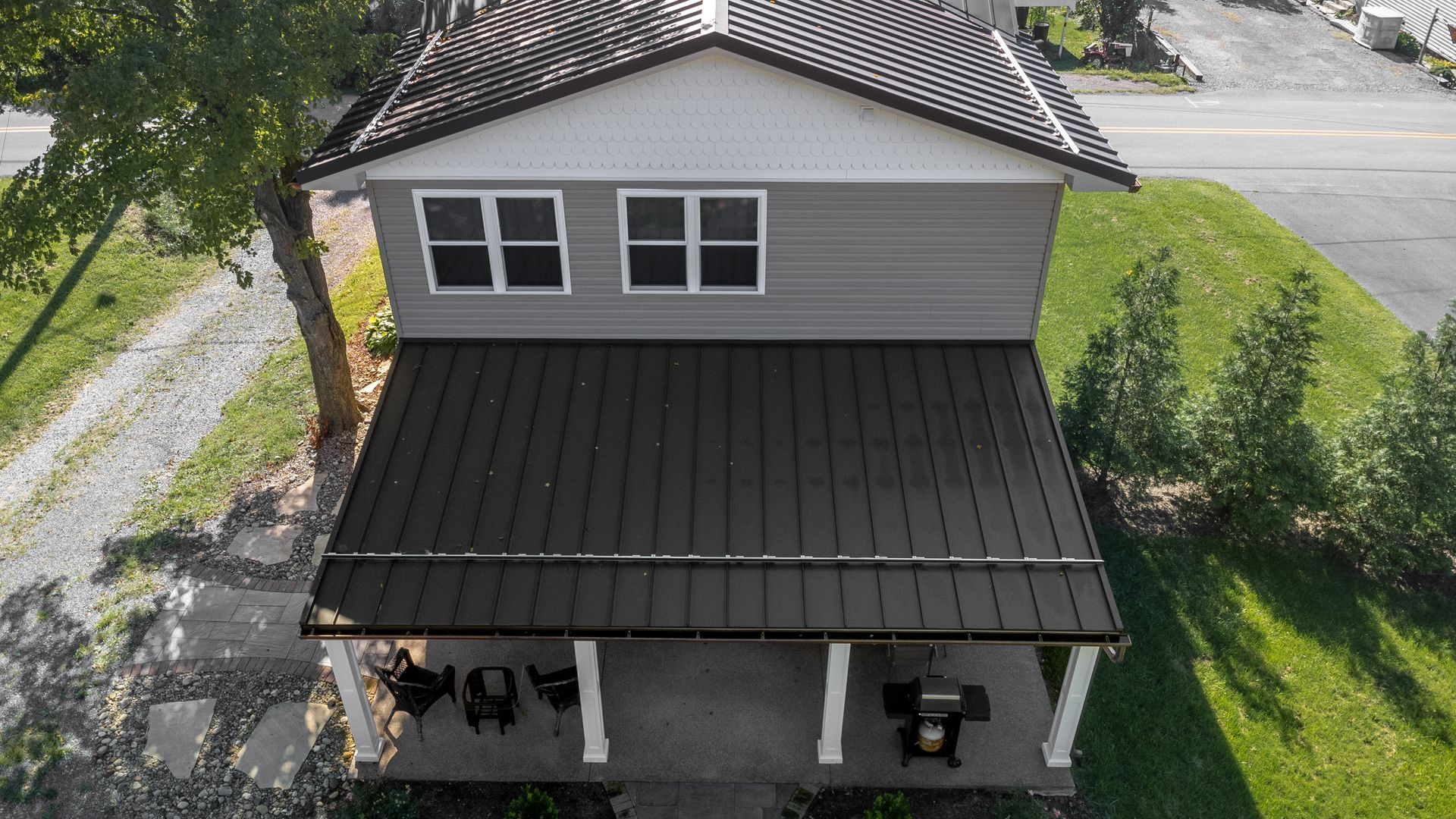 Two-story house with a gray exterior and dark gray roof. Has a porch with white columns.