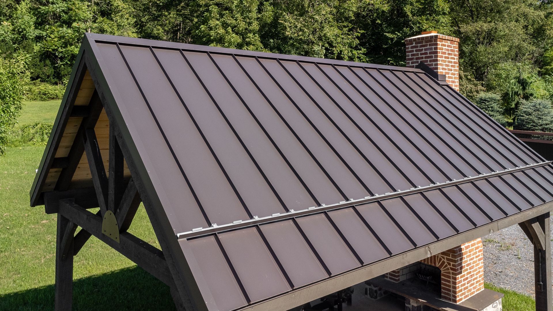 Brown metal roof on a gazebo with a brick chimney; outdoors, sunny.