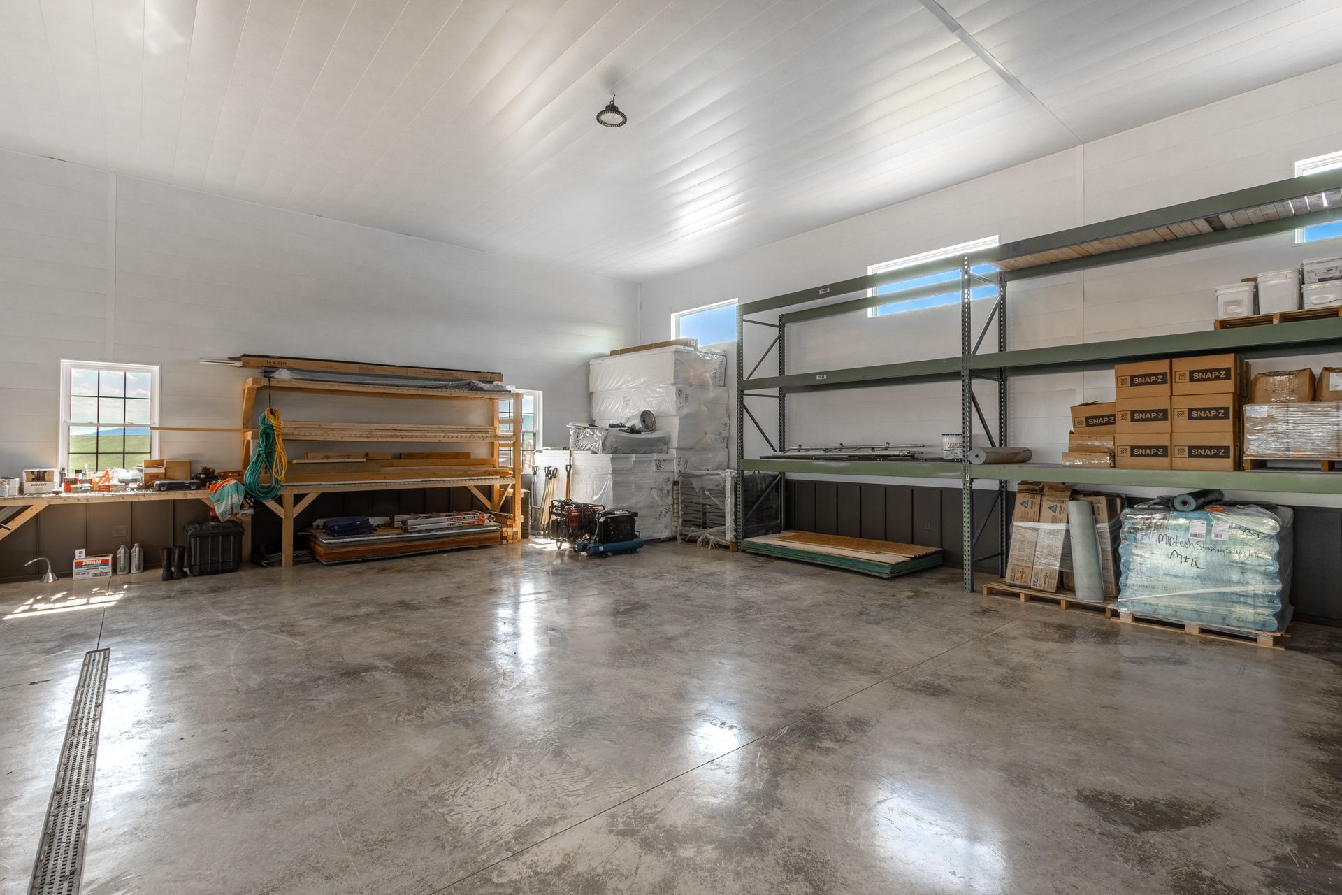 Warehouse interior with shelving, boxes, and work tables. Bright with concrete floor.