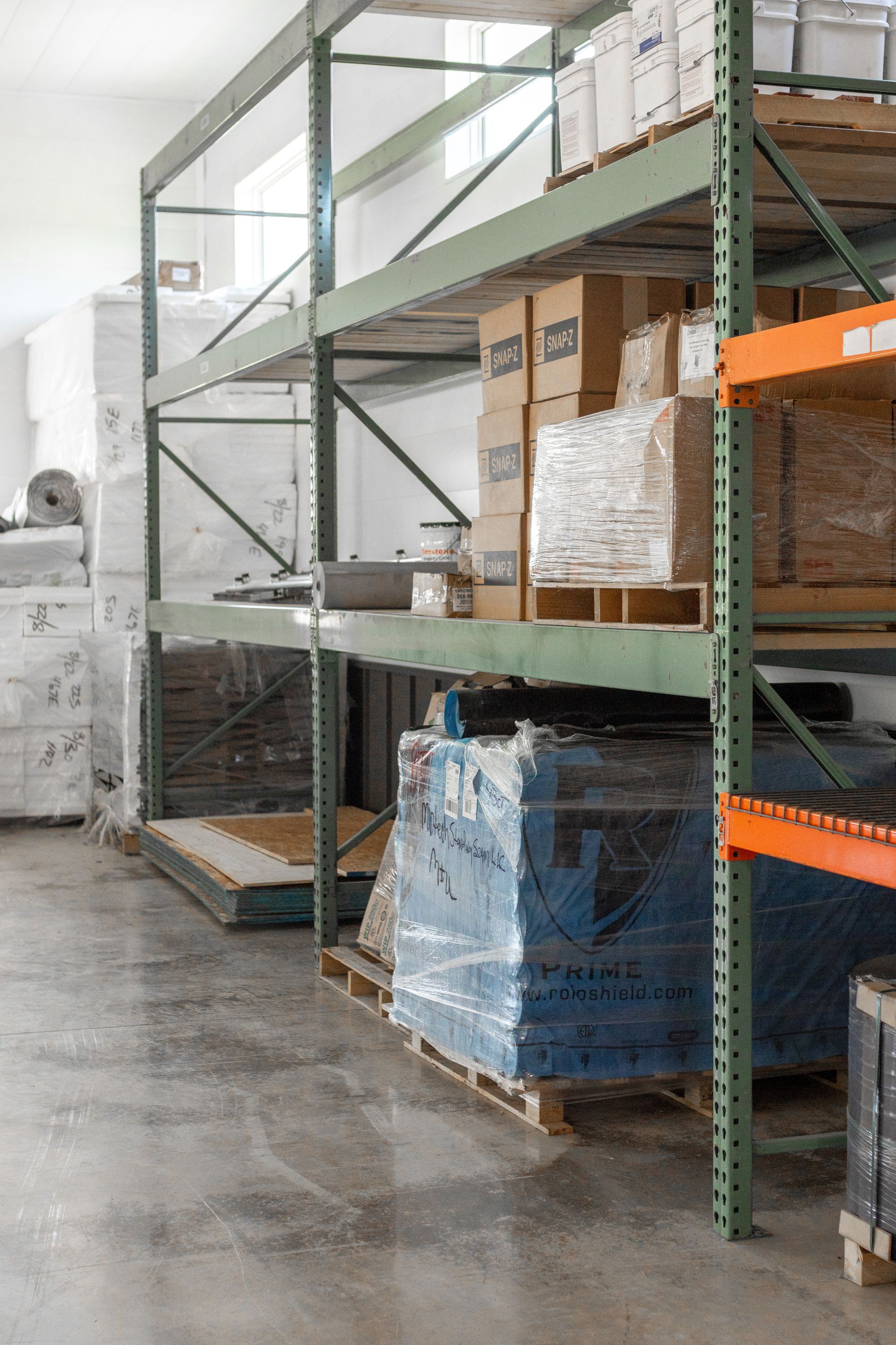 Warehouse interior with tall metal shelves holding boxes and pallets.