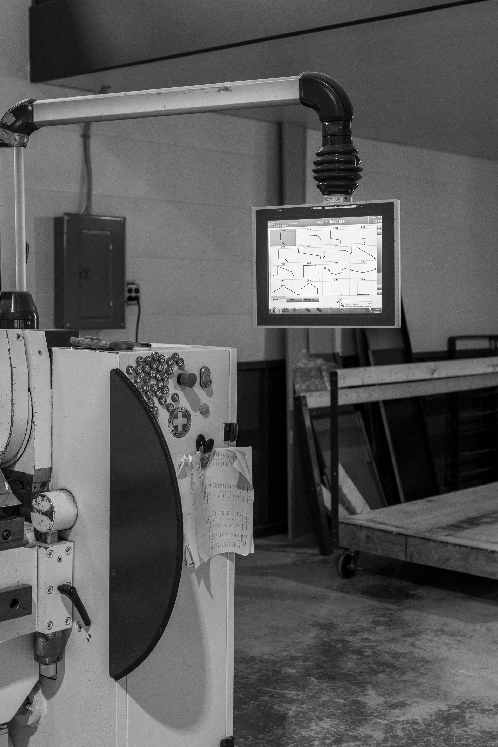 A workstation with a computer monitor suspended above it in a workshop setting.