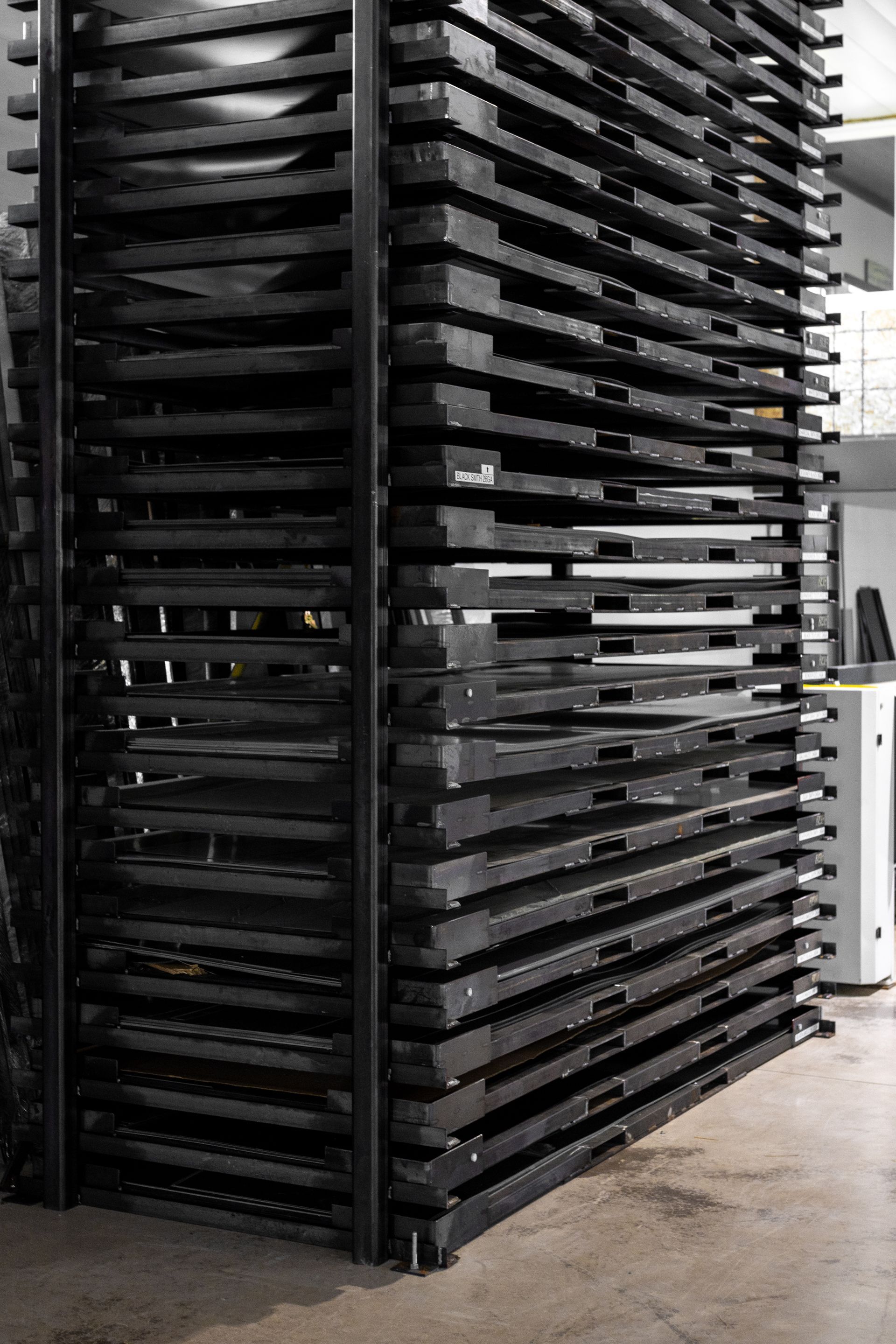 Stack of black plastic pallets in an industrial setting, neatly organized.
