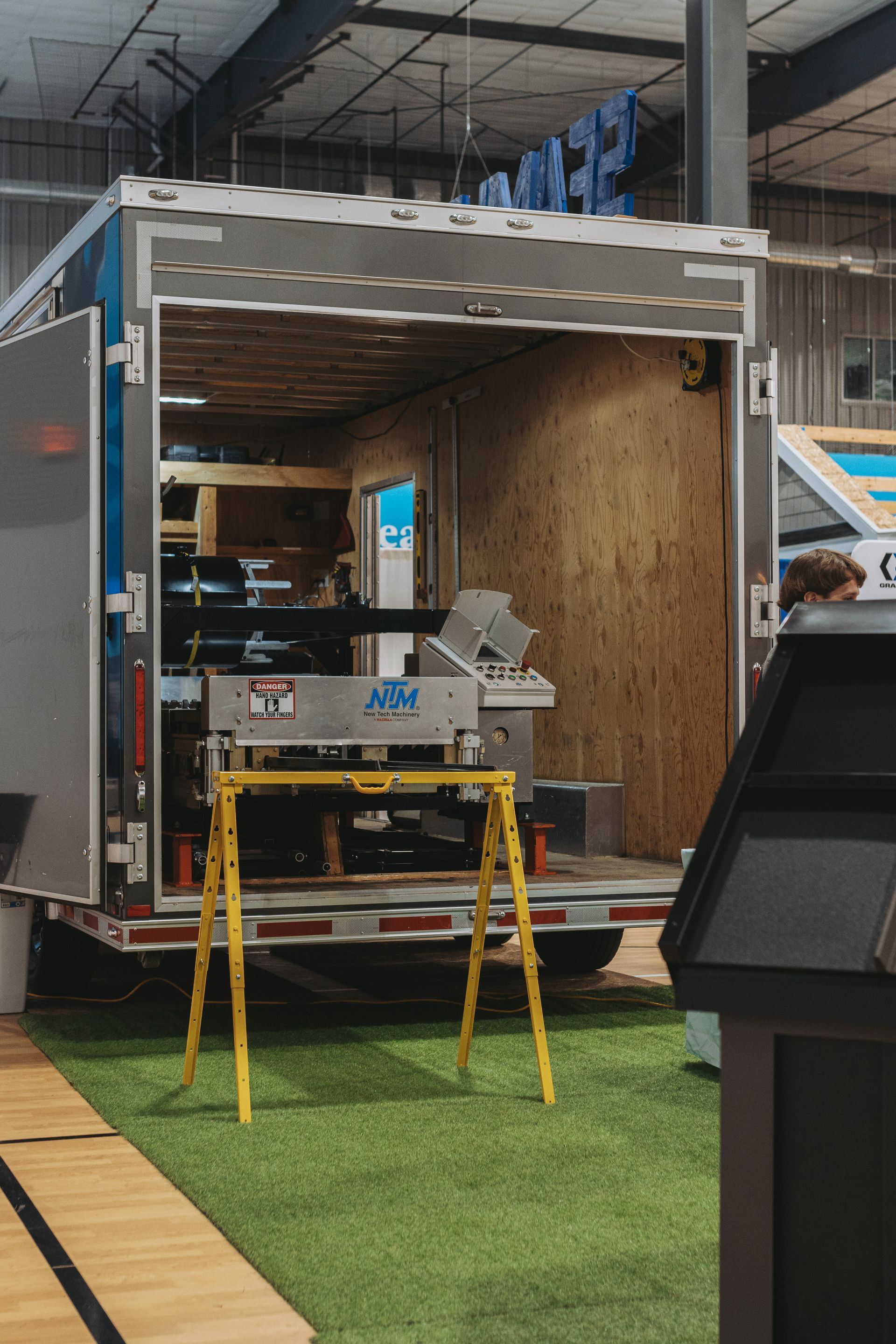 A mobile workshop with open doors, displaying tools and equipment on a yellow stand, inside a building.