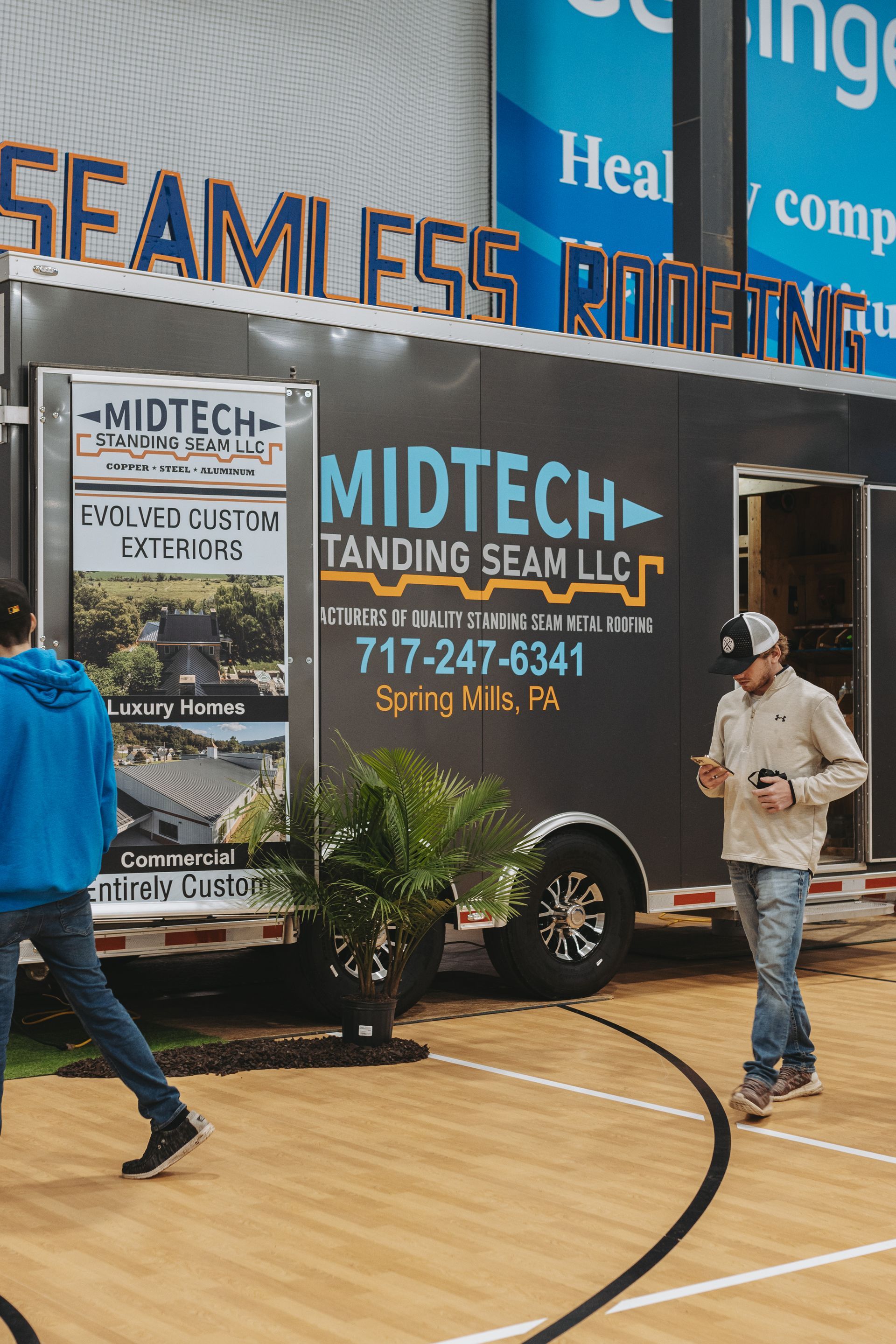 A man walks by a trailer for Midtech Standing Seam roofing at a trade show.