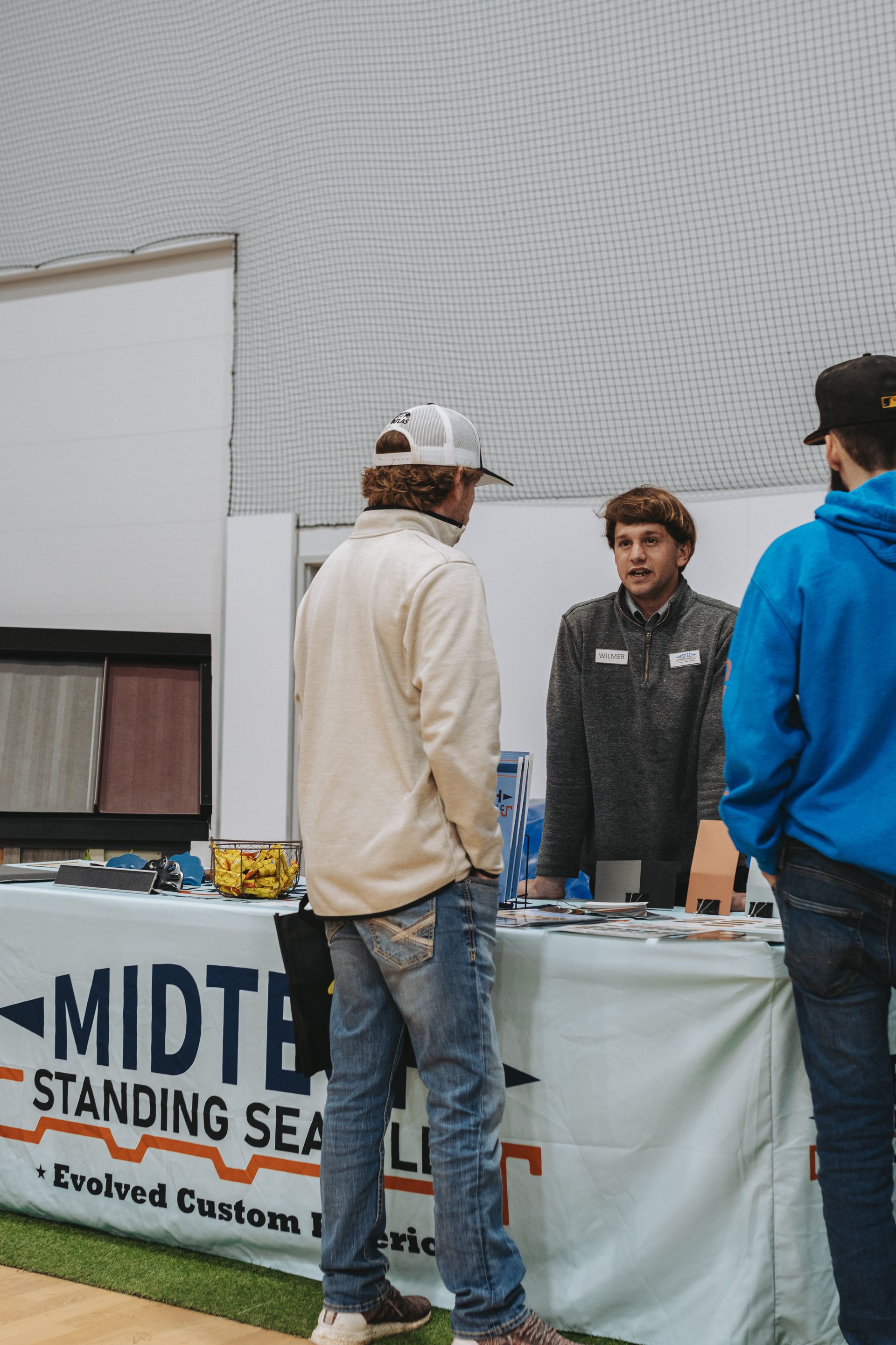 Three men at a trade show booth with a 