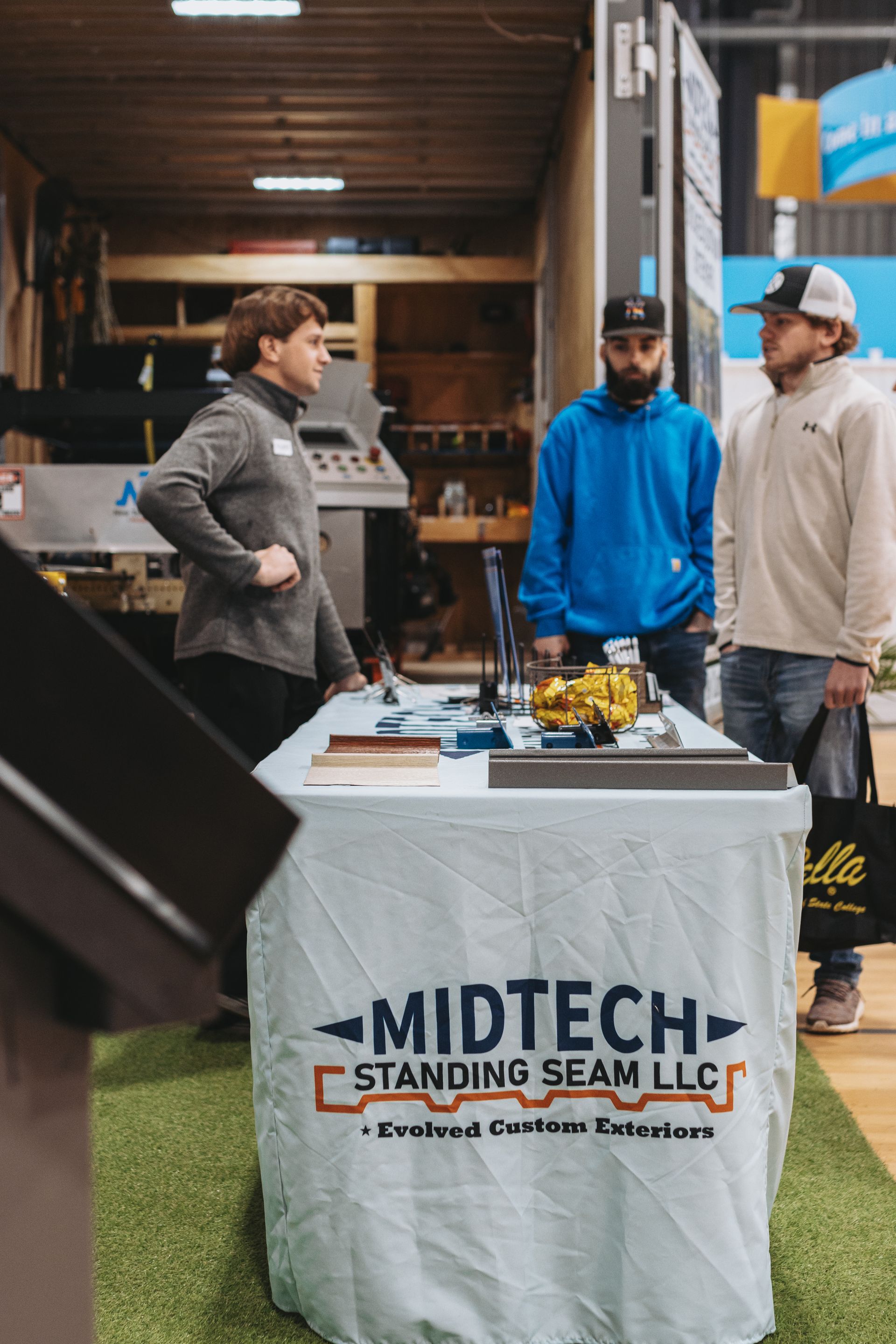 Three men at a trade show booth with a 