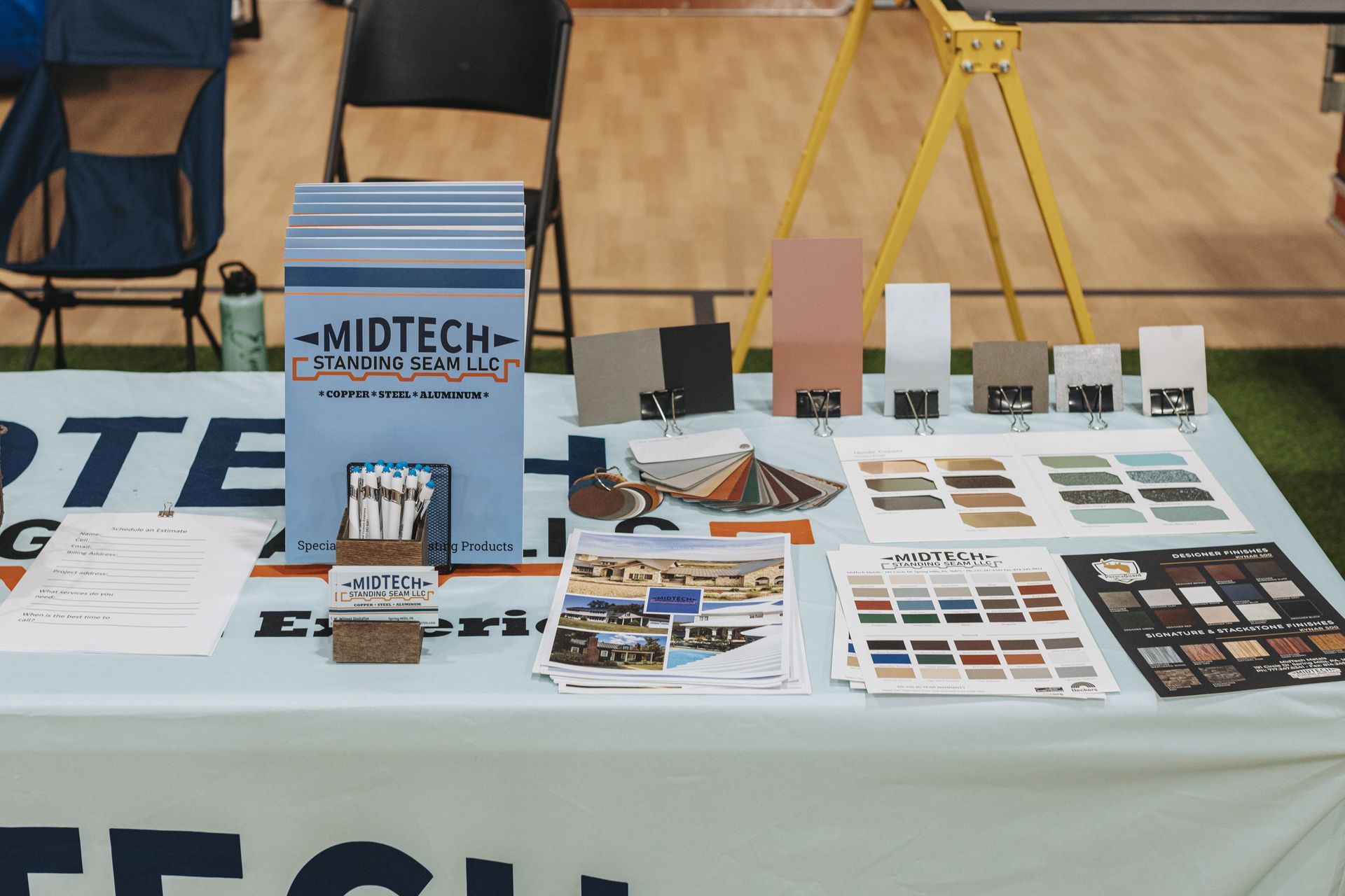 Midtech Construction booth at a trade show, with samples, brochures, and color swatches on display.