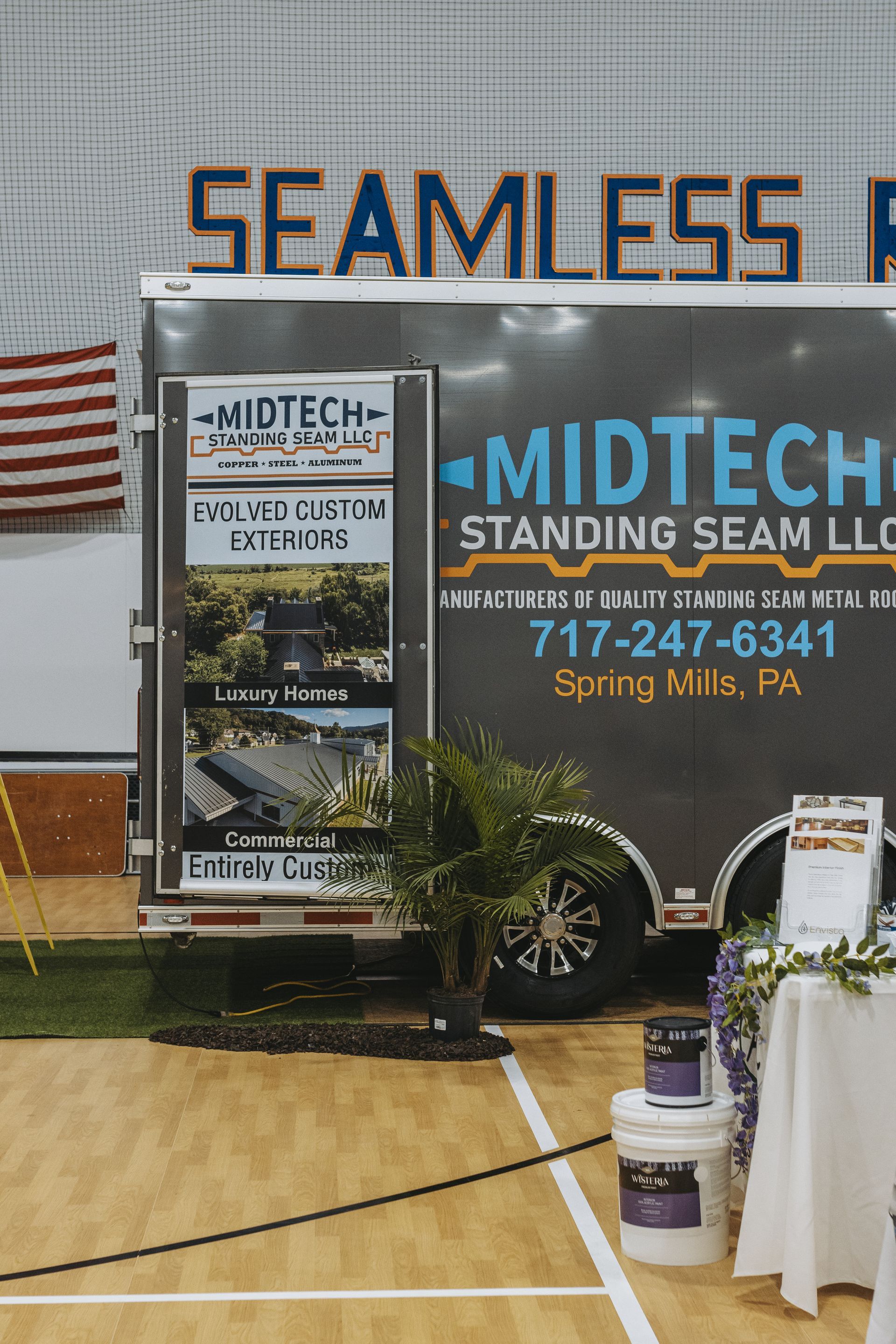 A trailer for Midtech Standing Seam LLC at a show. The trailer is dark with logos and graphics.