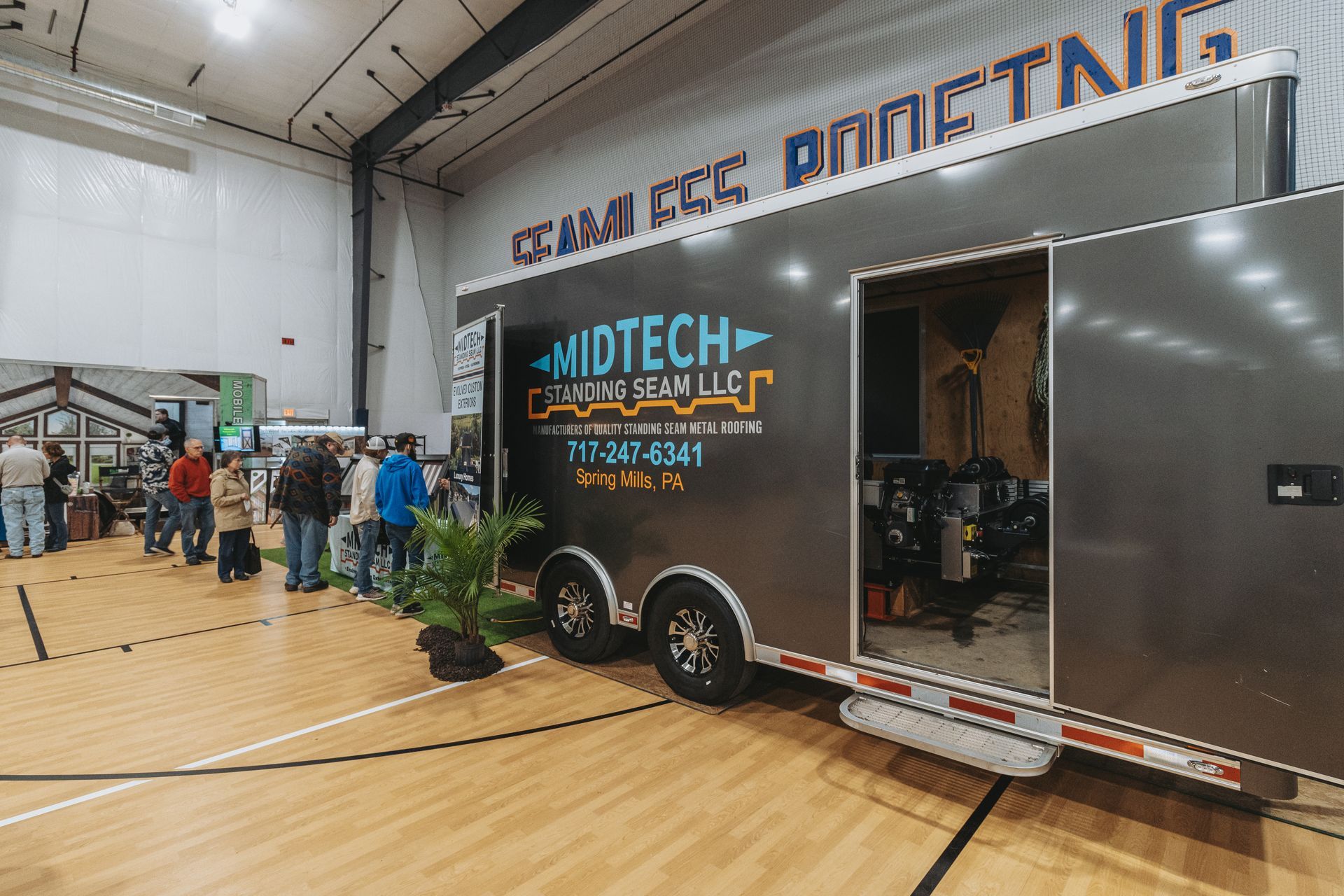 A trailer for Midtech at an event with people in a gymnasium. The trailer is open, and has plants.