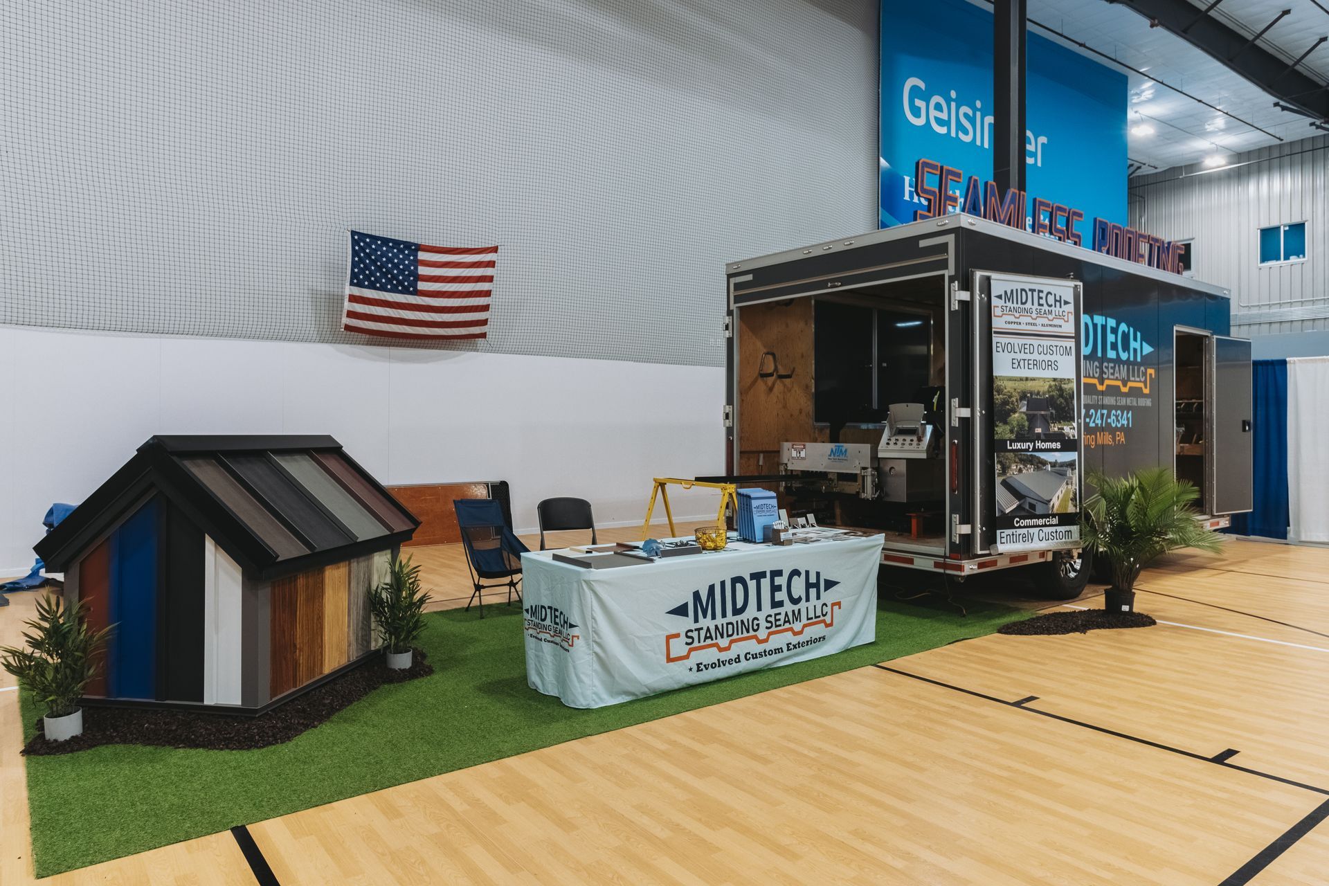 A booth at an event with a trailer, demo house, and signage.