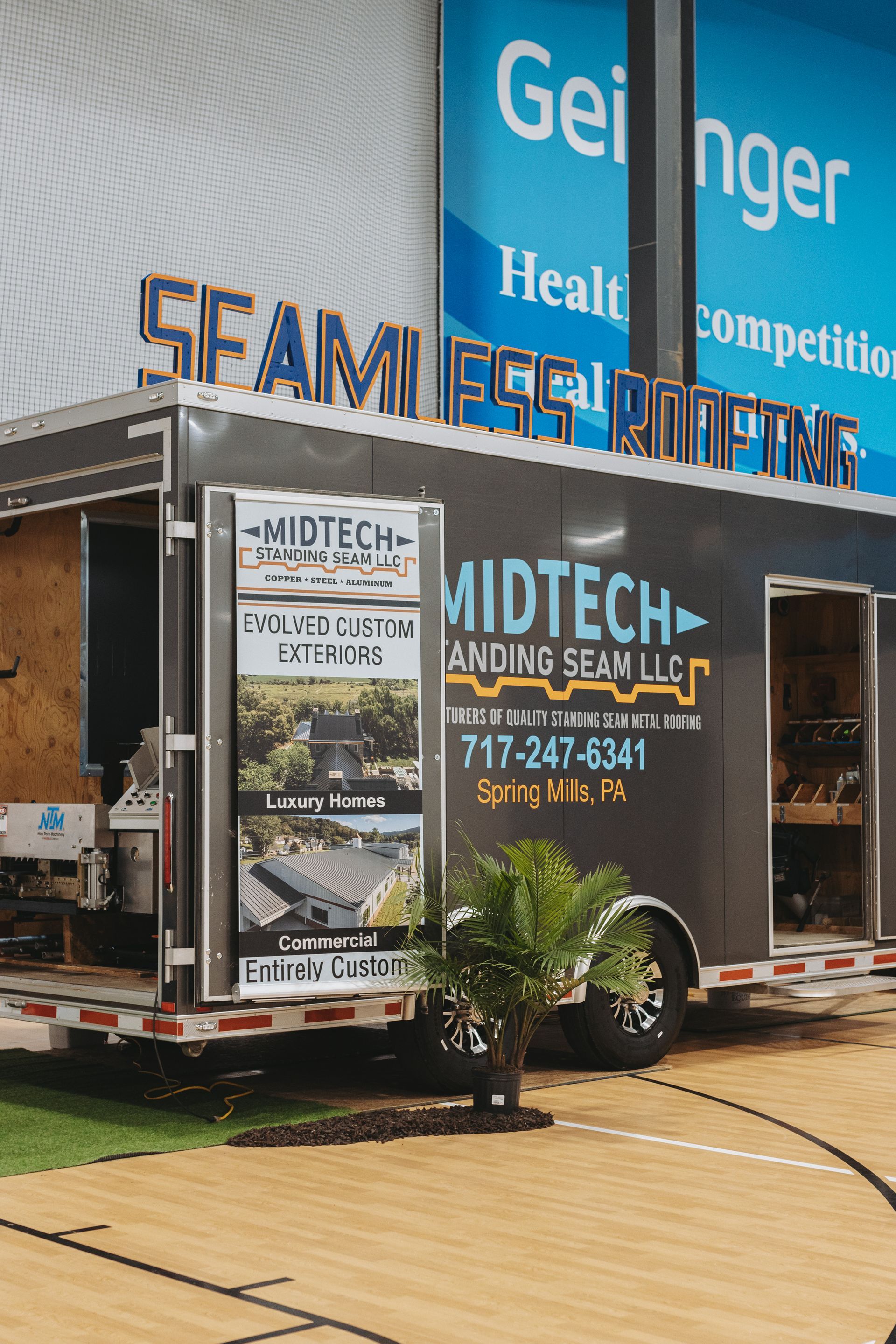 A mobile roofing display for Midtech Standing Seam, LLC at a convention. The trailer is grey with signage.