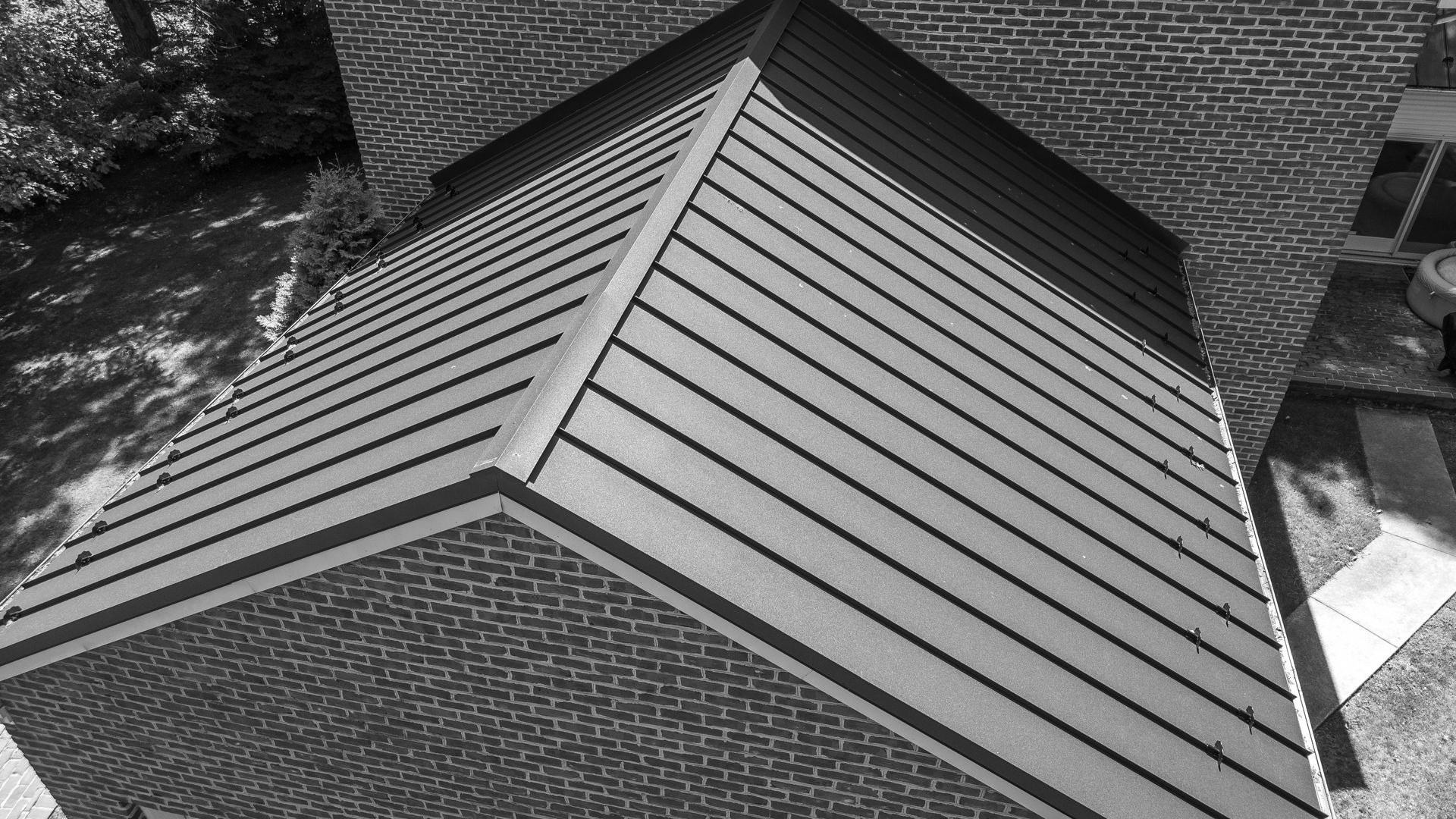 Brick building with a dark metal roof angled towards the viewer on a sunny day.