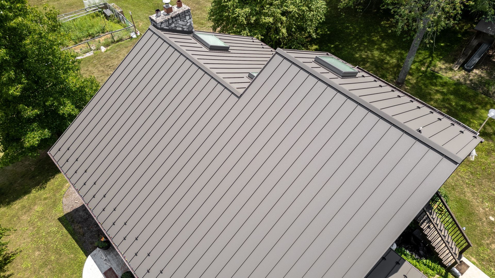 Brown metal roof on a house with skylights and a chimney, viewed from above.