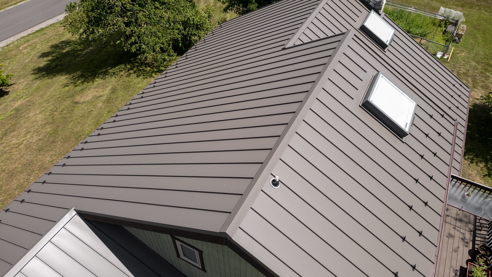 Gray metal roof with skylights on a house, seen from above.
