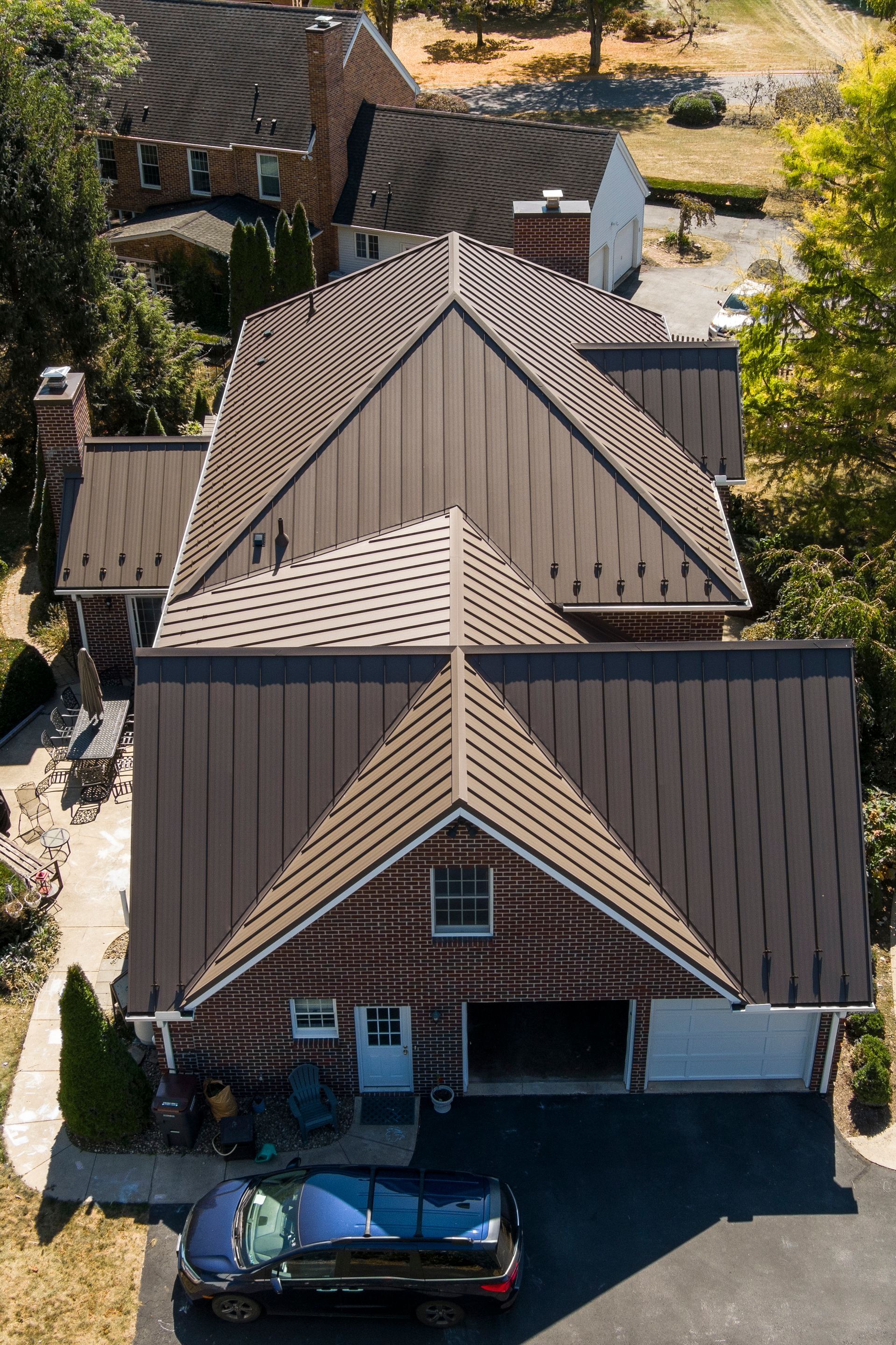 An aerial view of a dark metal-roofed residential brick house