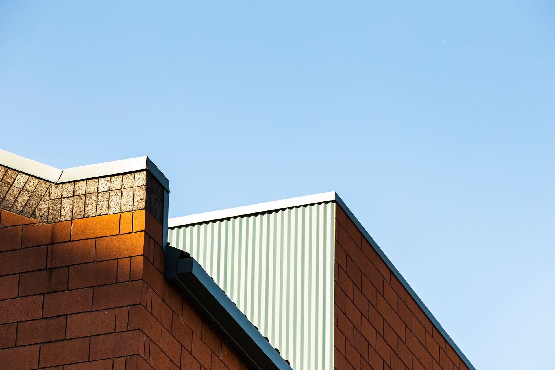 Triangular roof of a modern State College building with dark brown panels and light brown beams, sta