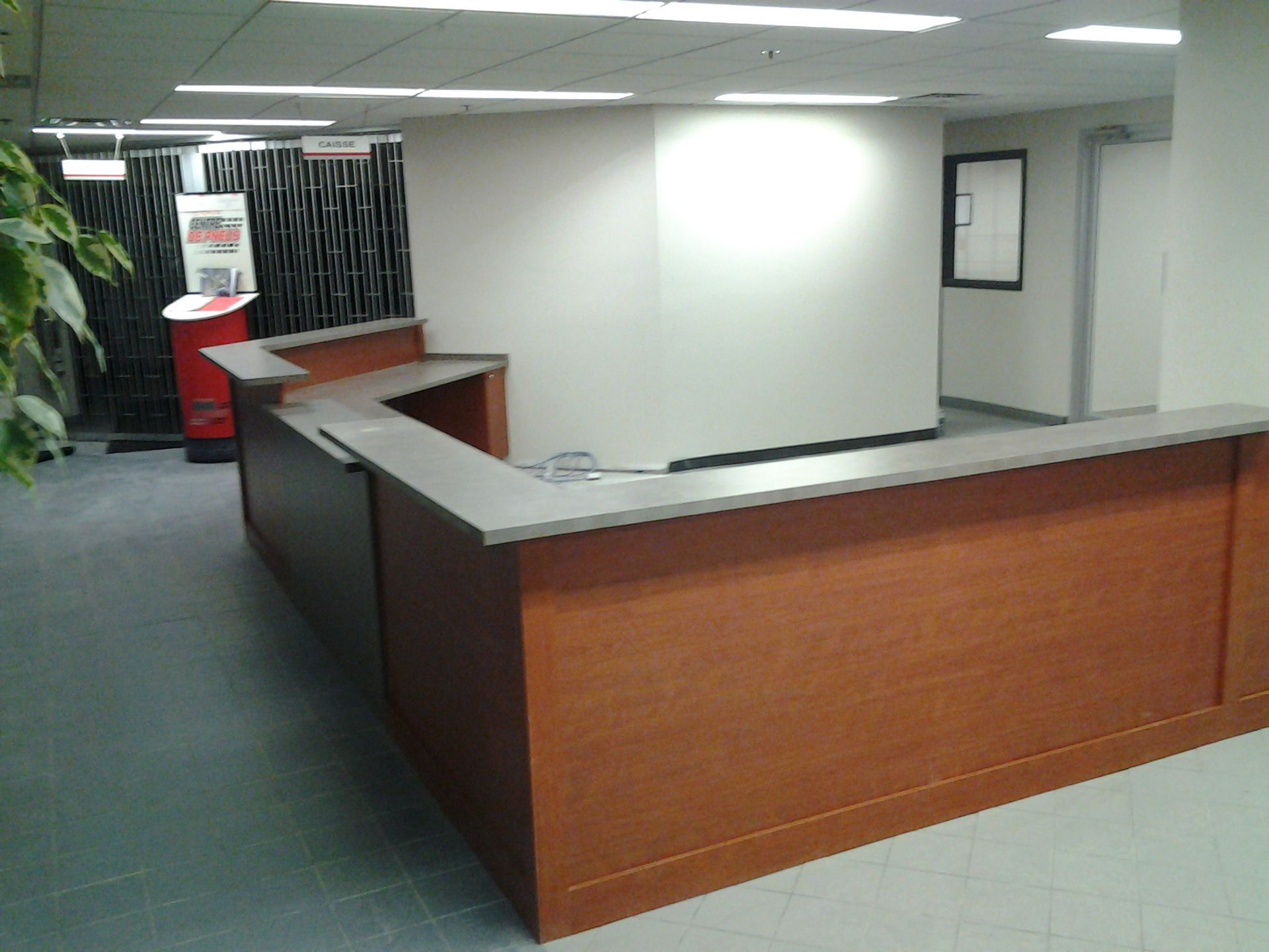 Bureau d'accueil en bois dans un bureau moderne. Comptoir gris et murs clairs.