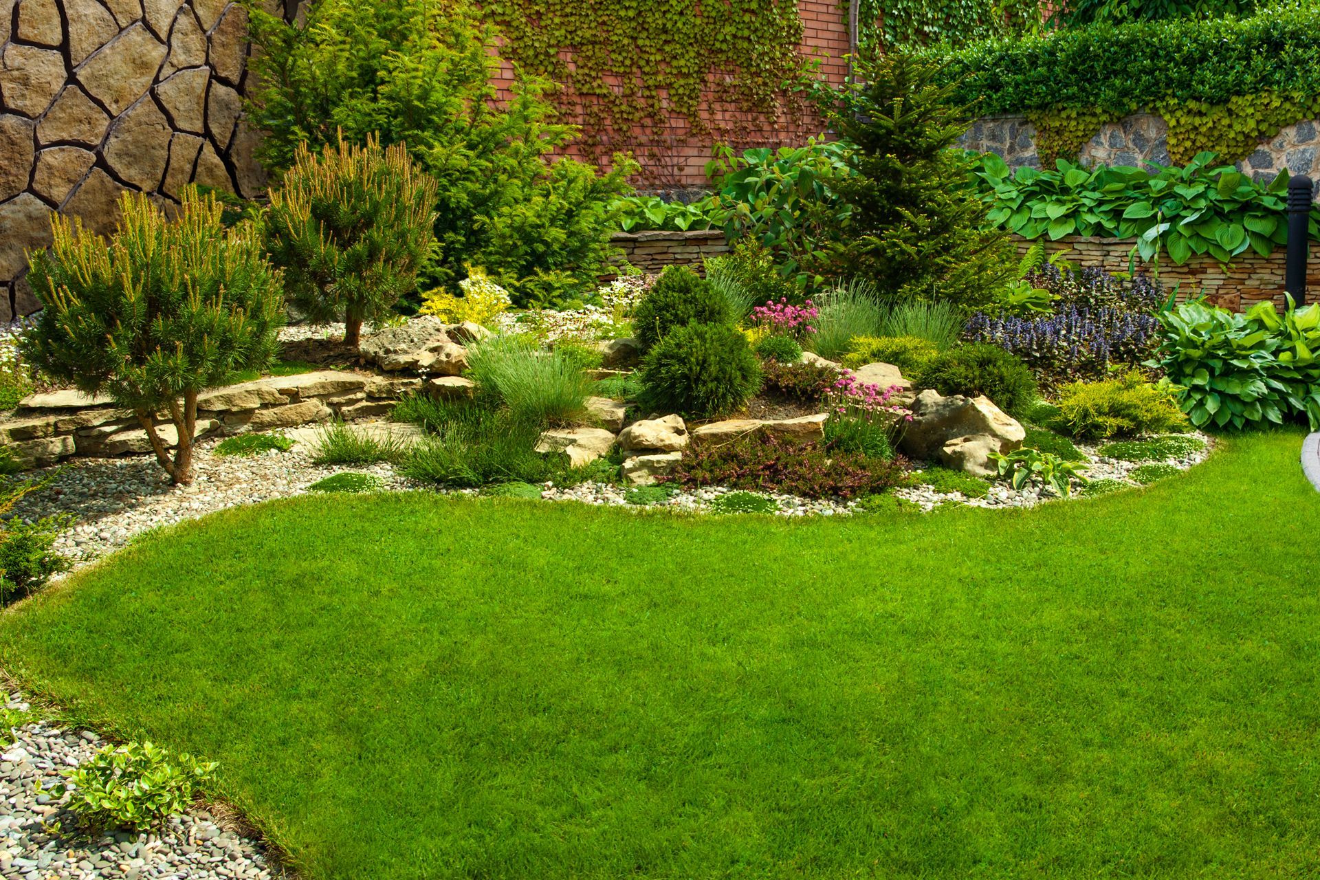 A lush green lawn surrounded by trees and rocks in a garden