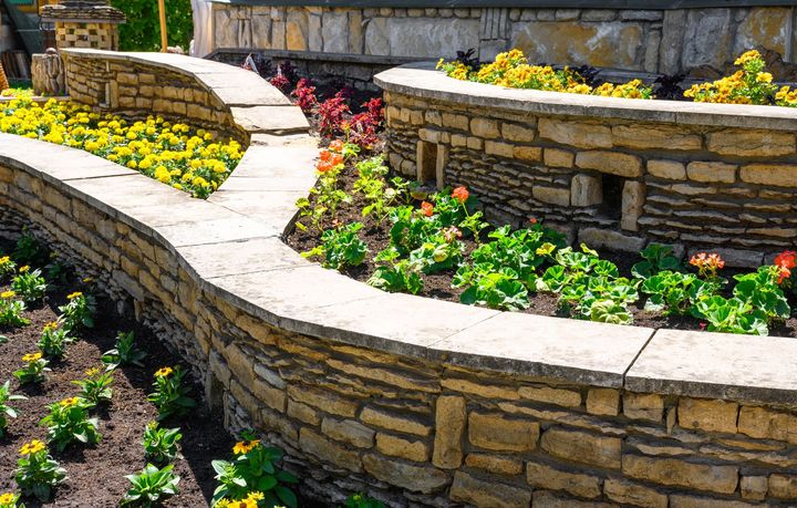 A stone wall surrounded by flowers in a garden