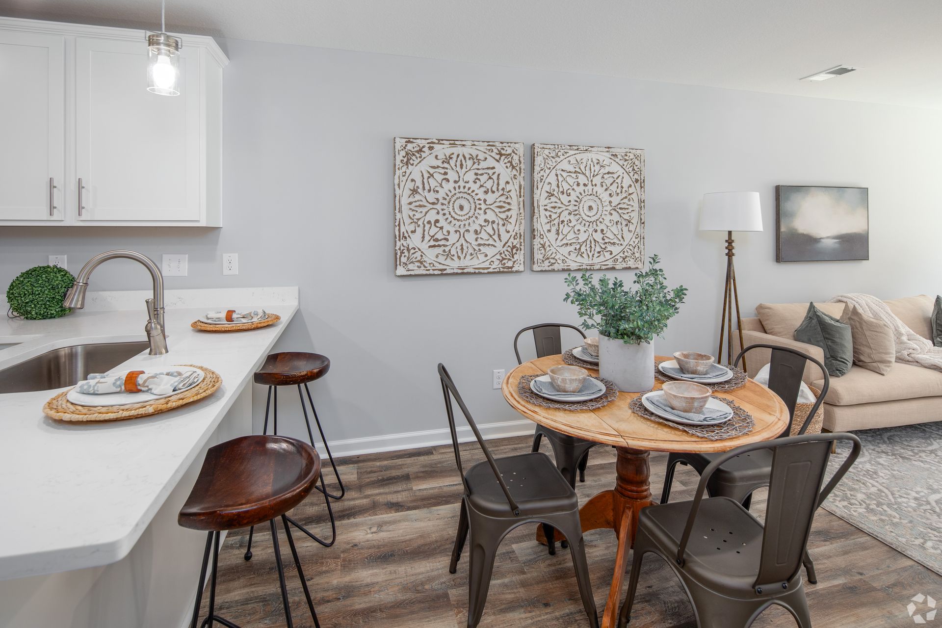 Kitchen and dining area with a breakfast bar, round table, and a living room in the background.