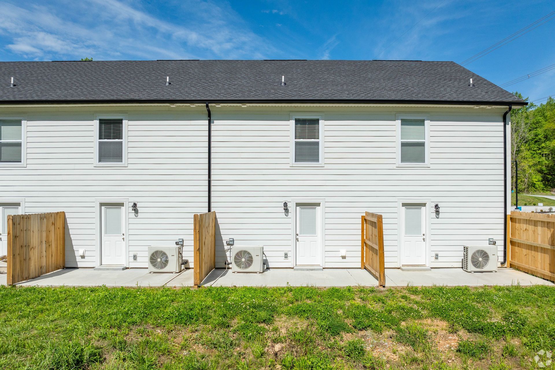 White townhouses with doors, windows, and air conditioning units under a blue sky.