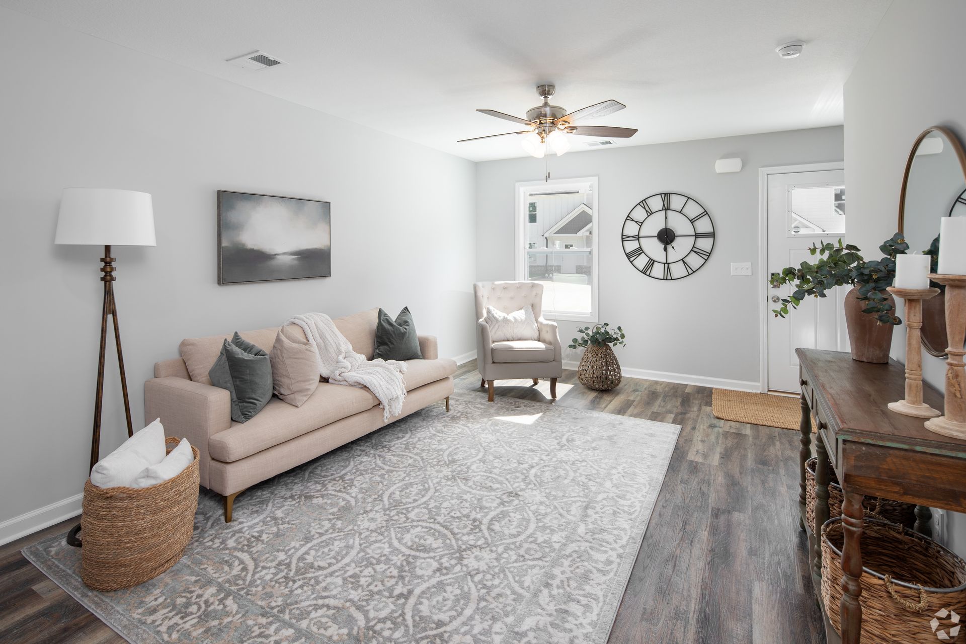 Living room with light gray walls, a pink couch, and a large rug.