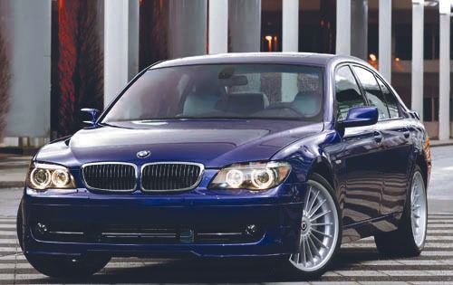 Blue BMW 7-Series sedan parked on a city street, silver wheels, daytime.