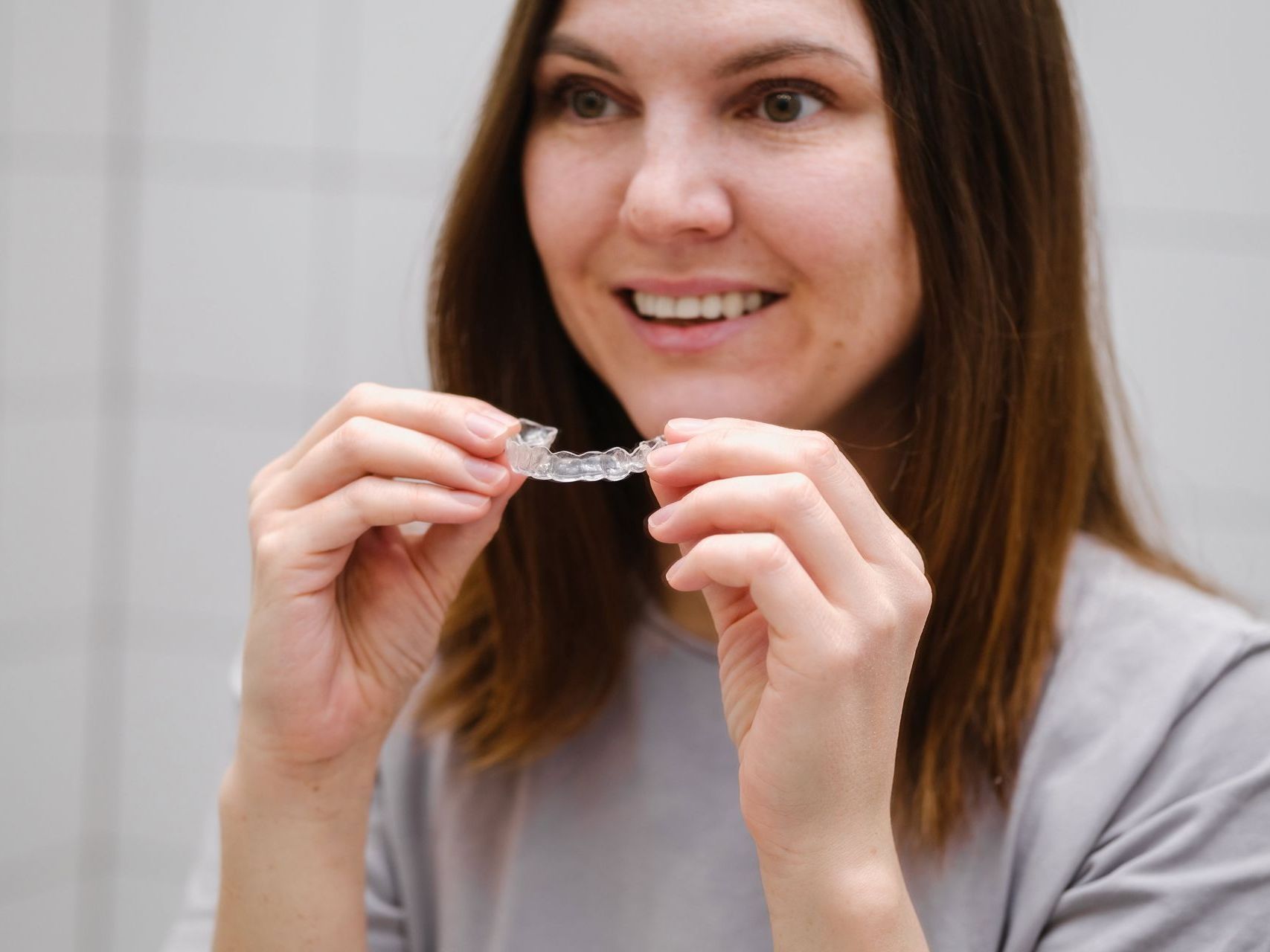 A woman is holding a clear brace in her hands and smiling