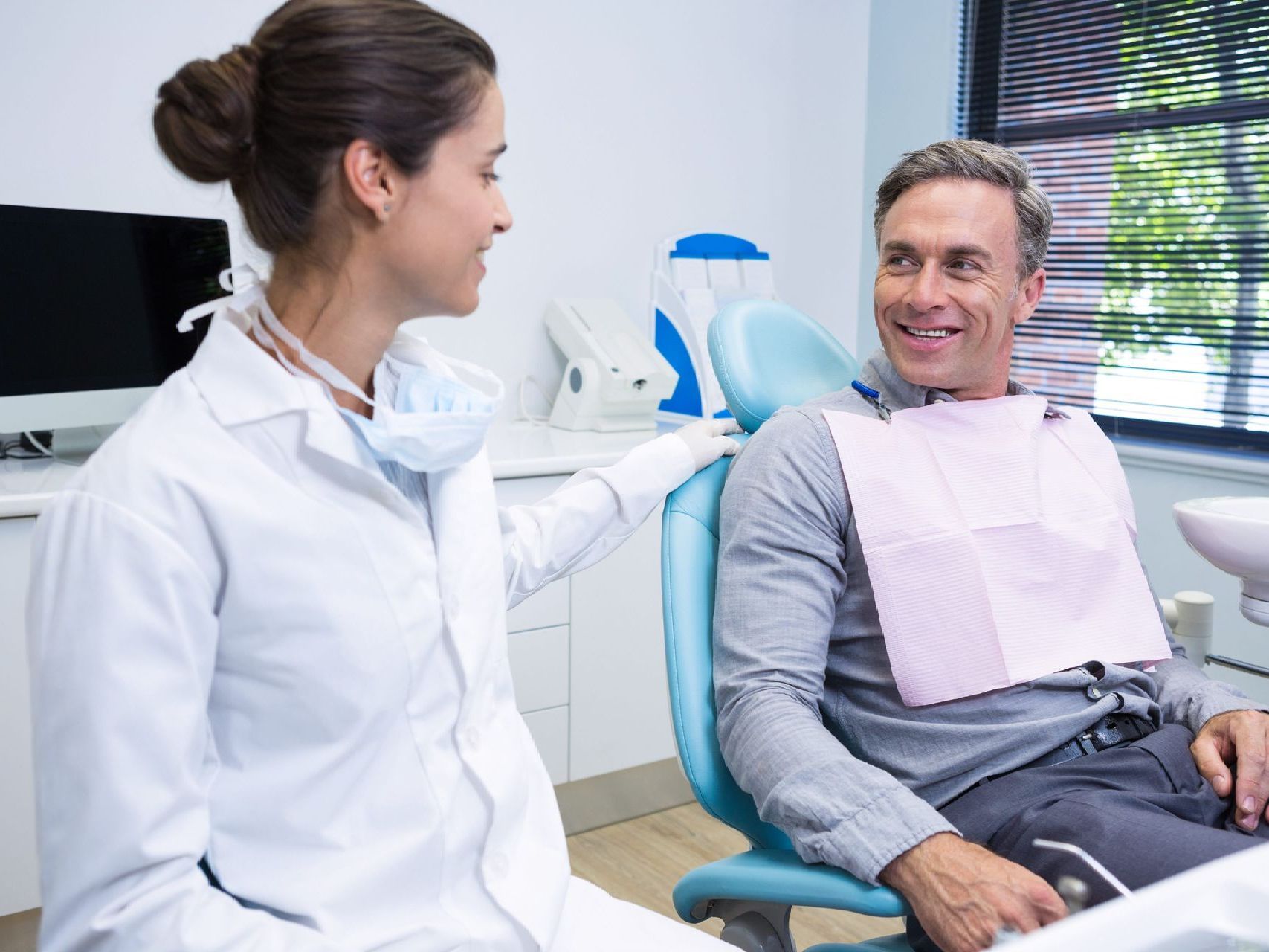 A dentist is talking to a patient in a dental chair