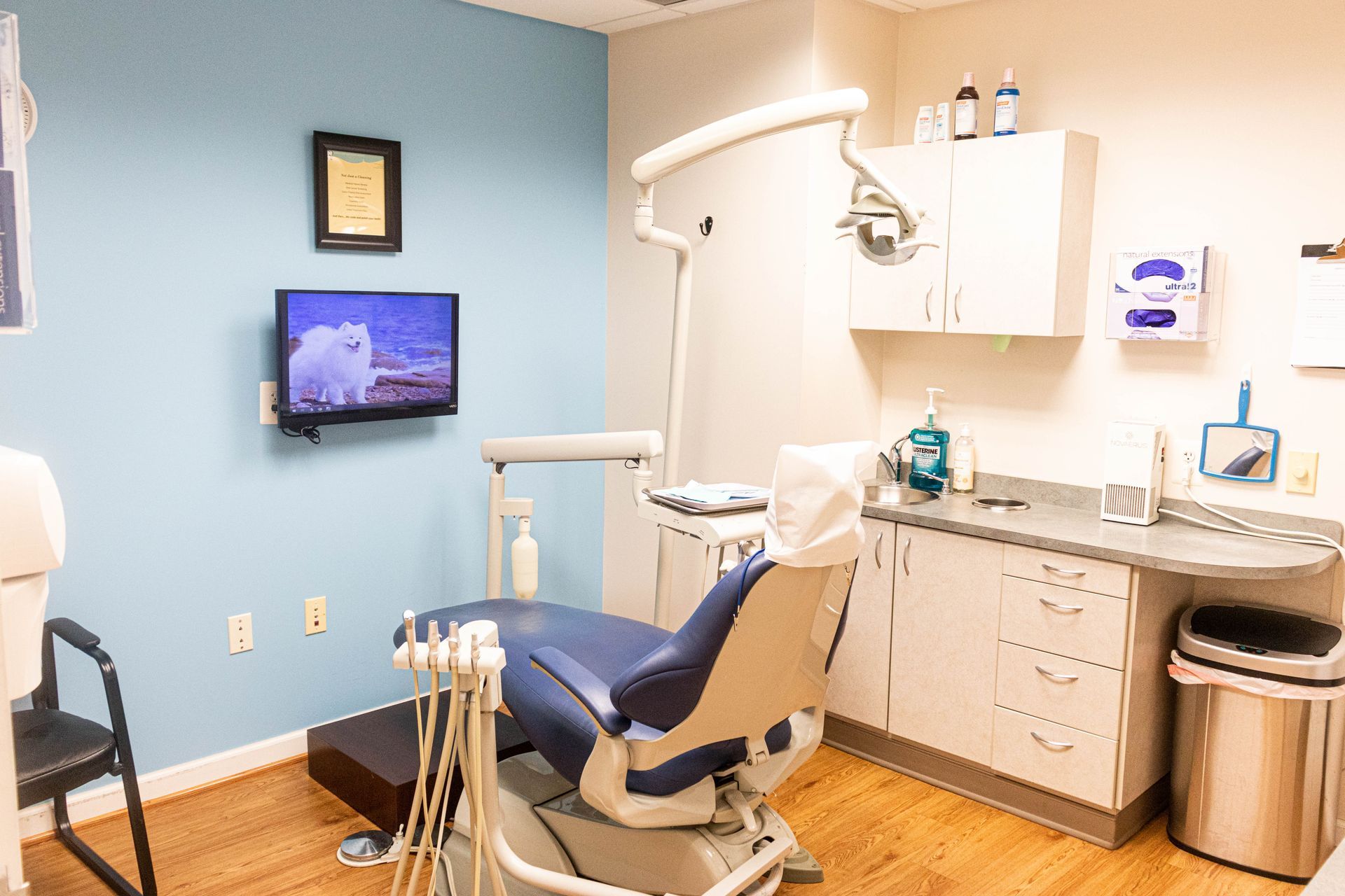 A dental office with a dental chair and a television on the wall