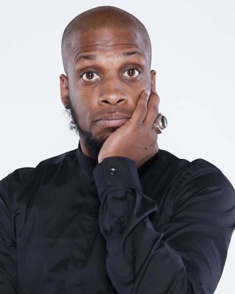 A man in a black shirt has his hand on his chin