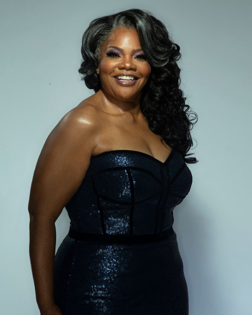 A woman in a black strapless dress smiles for the camera.