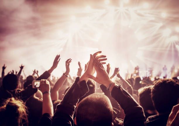 A crowd of people are raising their hands in the air at a concert.