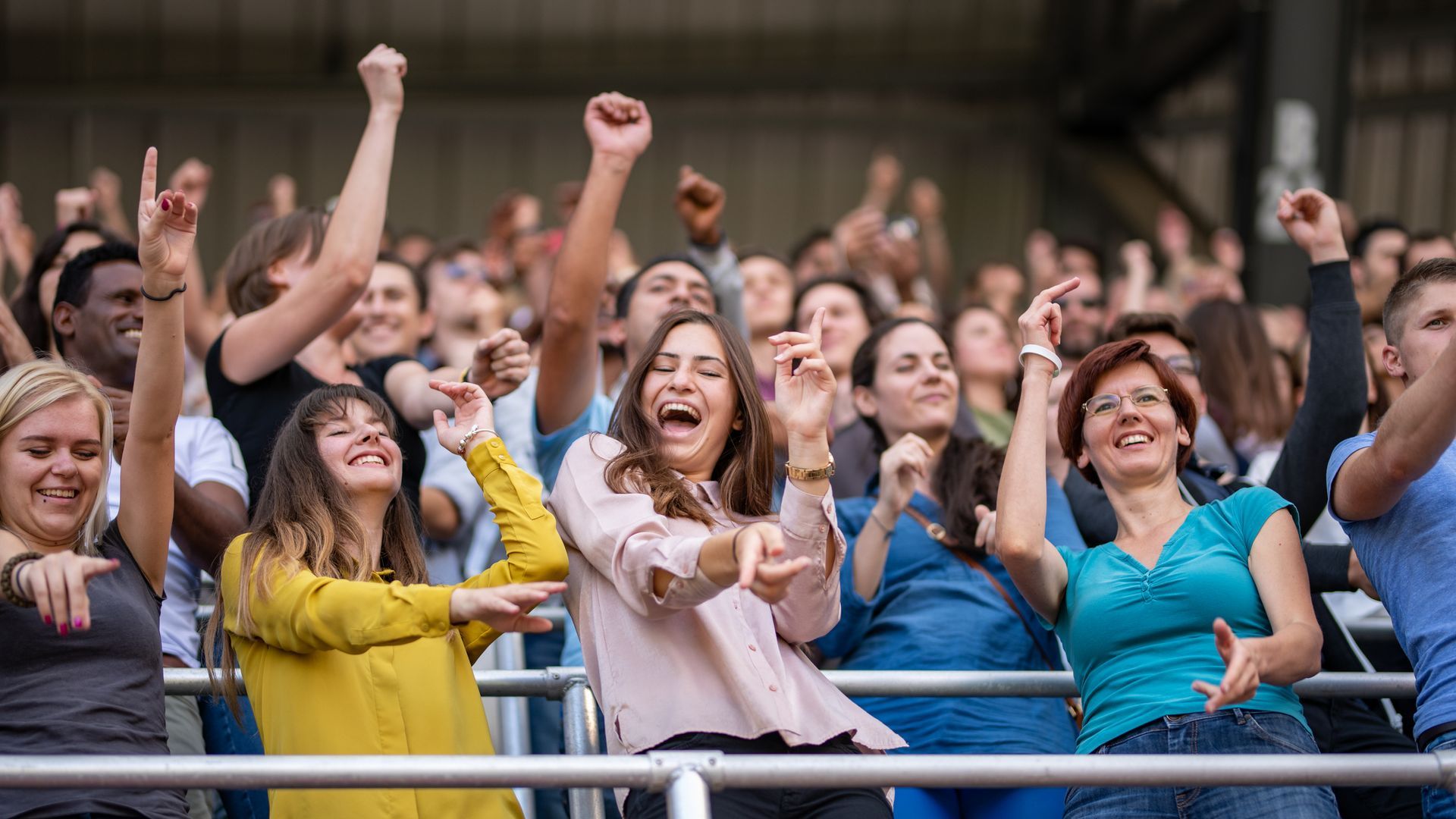 A crowd of people are standing in a stadium with their arms in the air.