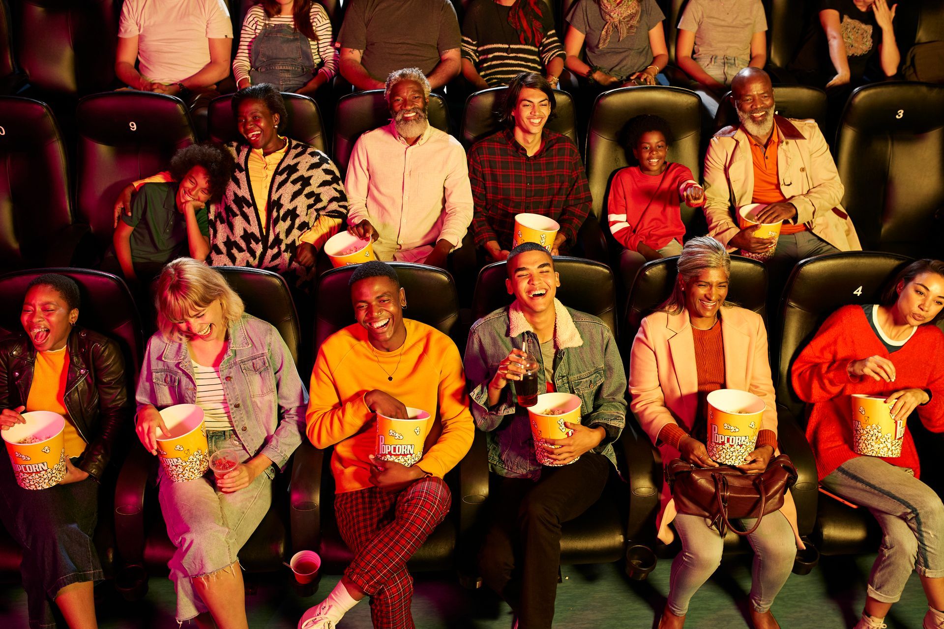 A group of people are sitting in a theater eating popcorn.