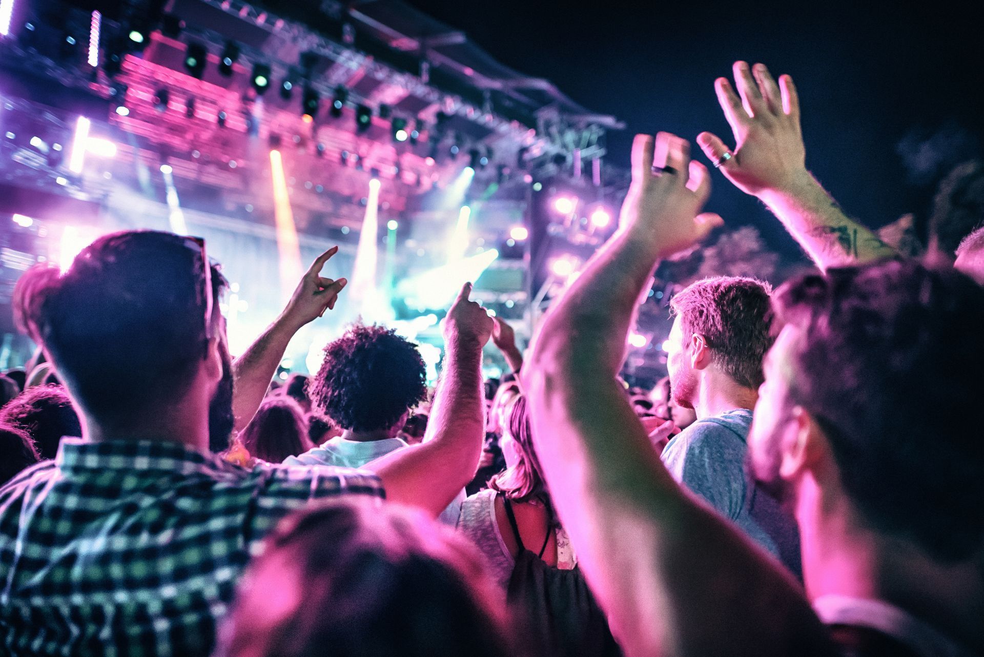 A crowd of people are raising their hands in the air at a concert.